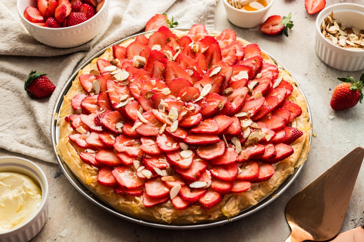 Side angle showing the layered phyllo crust and toppings on the full strawberry goat cheese tart.