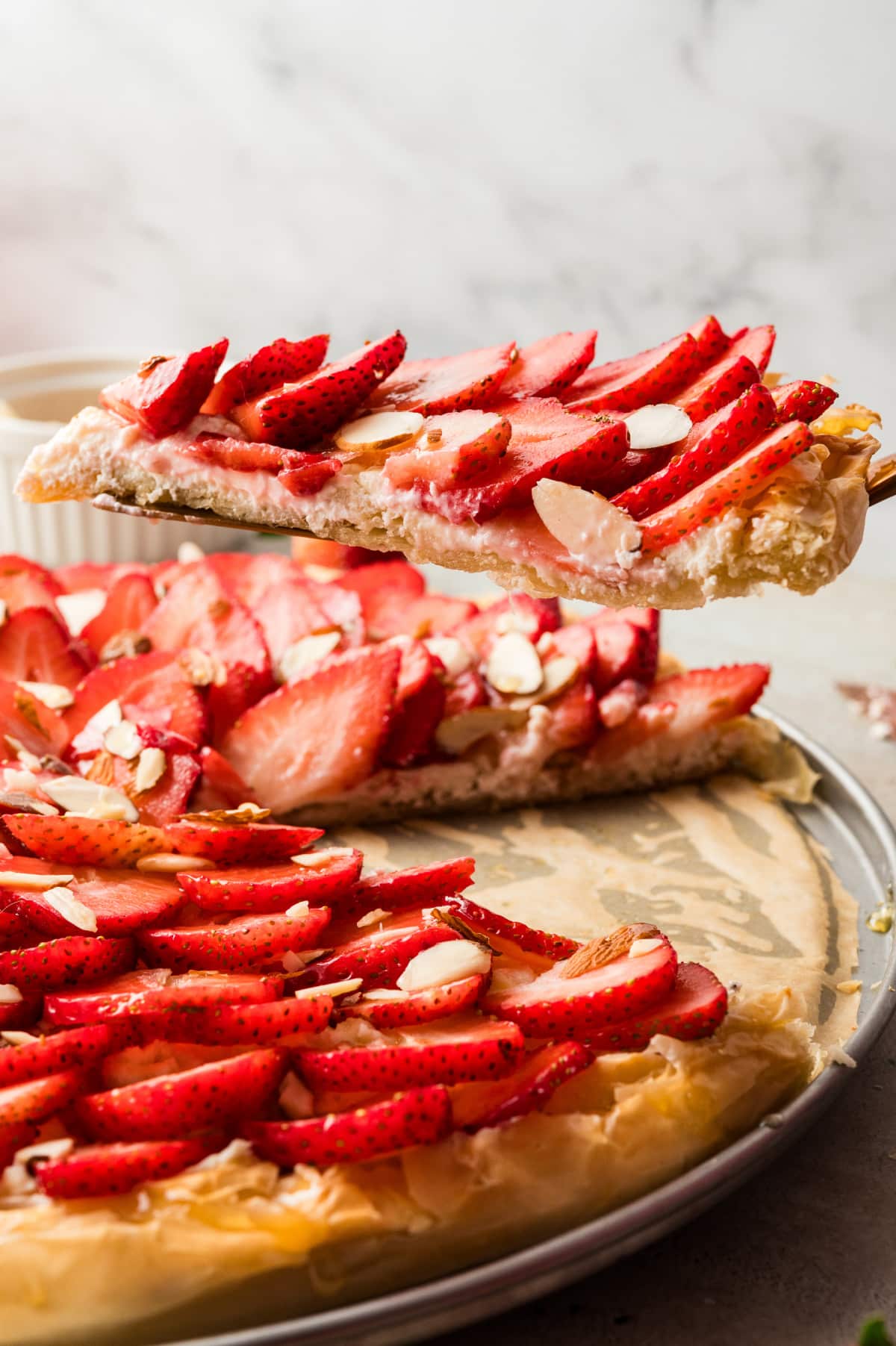 Side view of a slice being lifted from the tart, showing the flaky phyllo crust and creamy goat cheese layer.