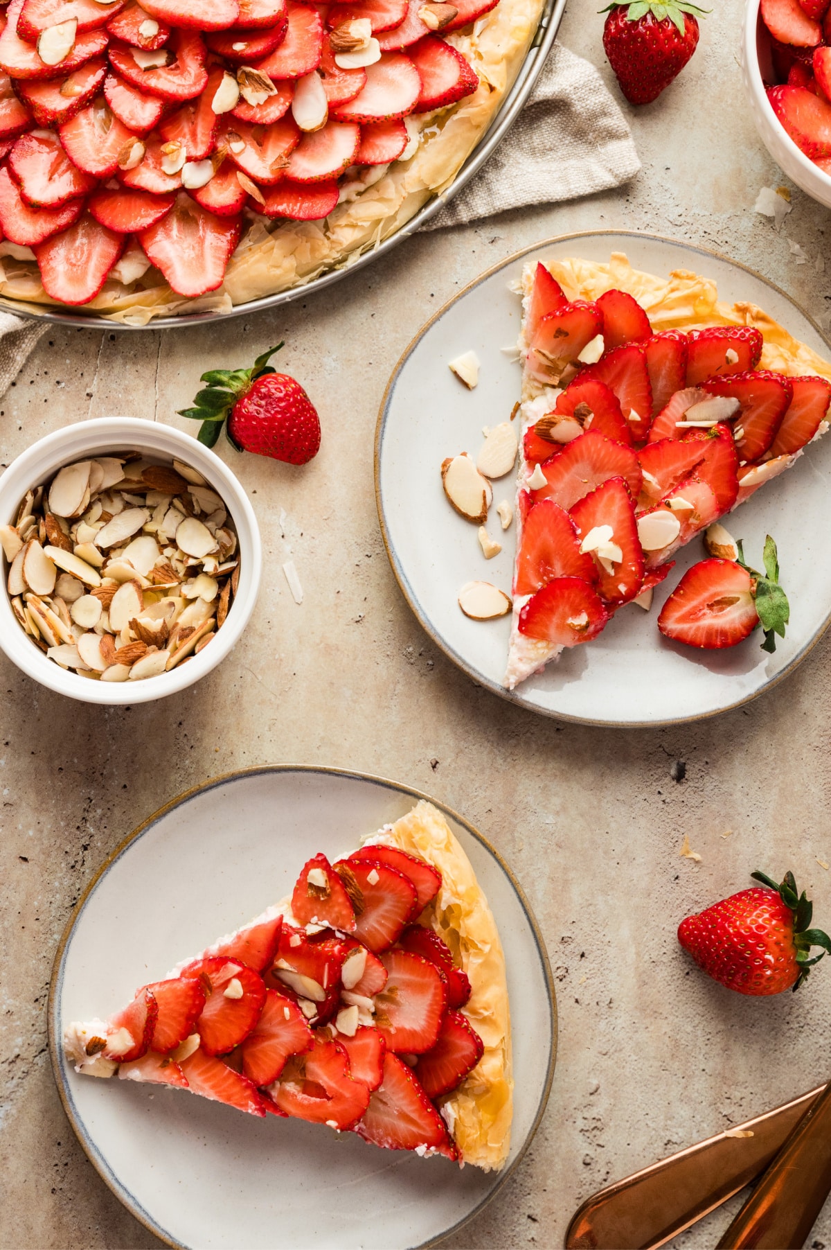 Overhead view of two slices of strawberry goat cheese tart served on plates, ready to eat.