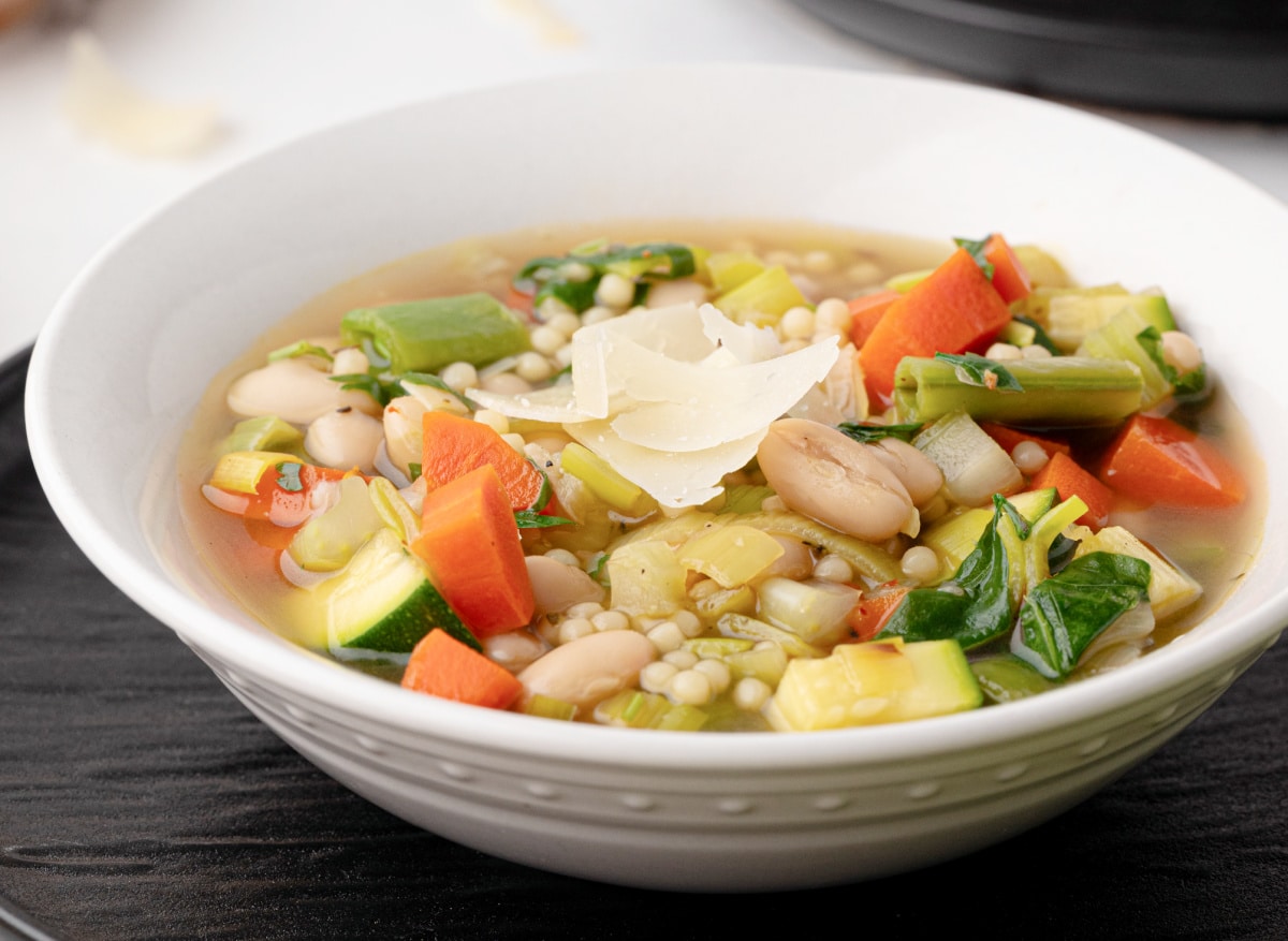 Side angle of green minestrone in a white bowl Side view of a bowl of green minestrone showing the broth, beans, and spring vegetables