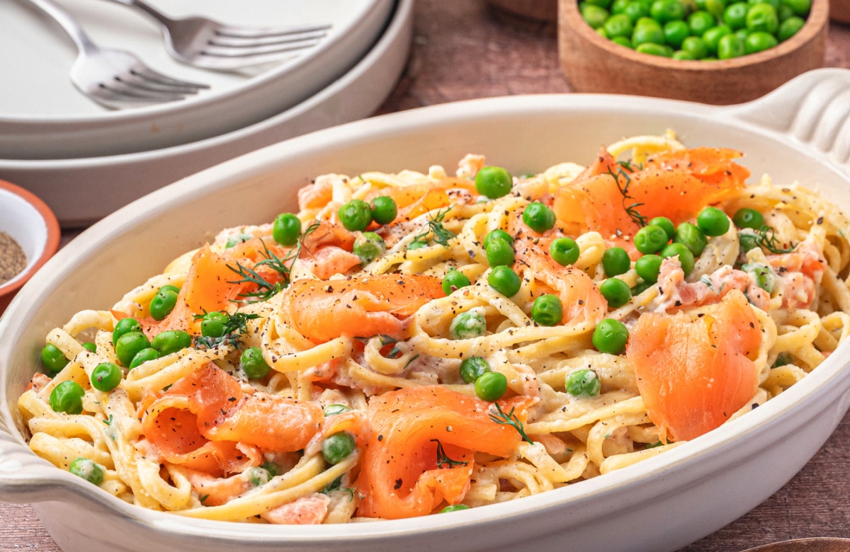 Creamy smoked salmon pasta with lemon and dill in a gratin baking dish. Side view of creamy smoked salmon pasta in a gratin dish.