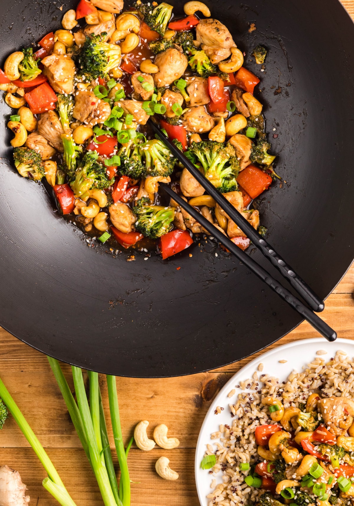 Overhead shot of cashew chicken in a wok next to a plated serving