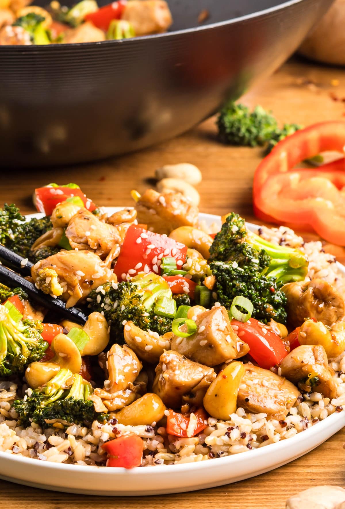 Close-up of sticky cashew chicken stir-fry with the wok in the background 