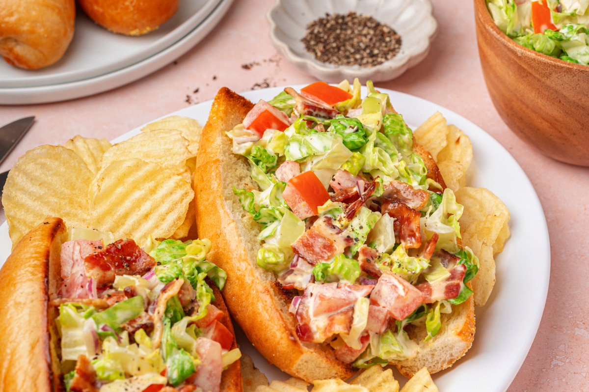 Two chopped BLT hoagies plated and ready to serve with toasted rolls and creamy bacon filling