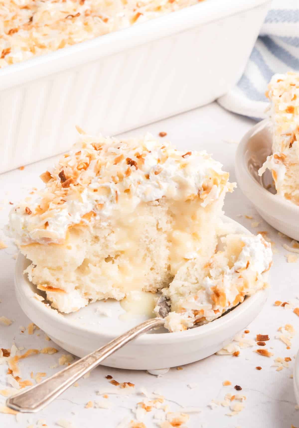Close side view of one slice of coconut poke cake with creamy filling oozing from the layers. 