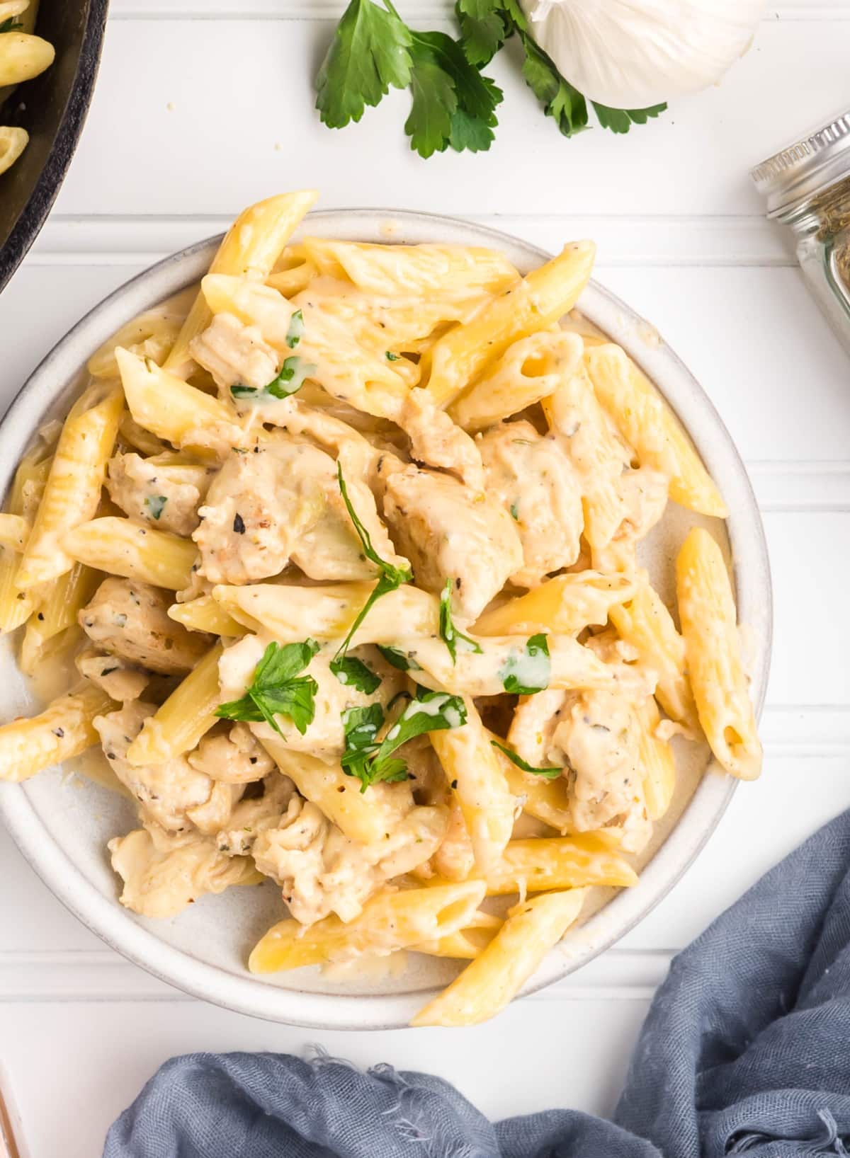 Plated garlic chicken pasta next to a blue napkin 