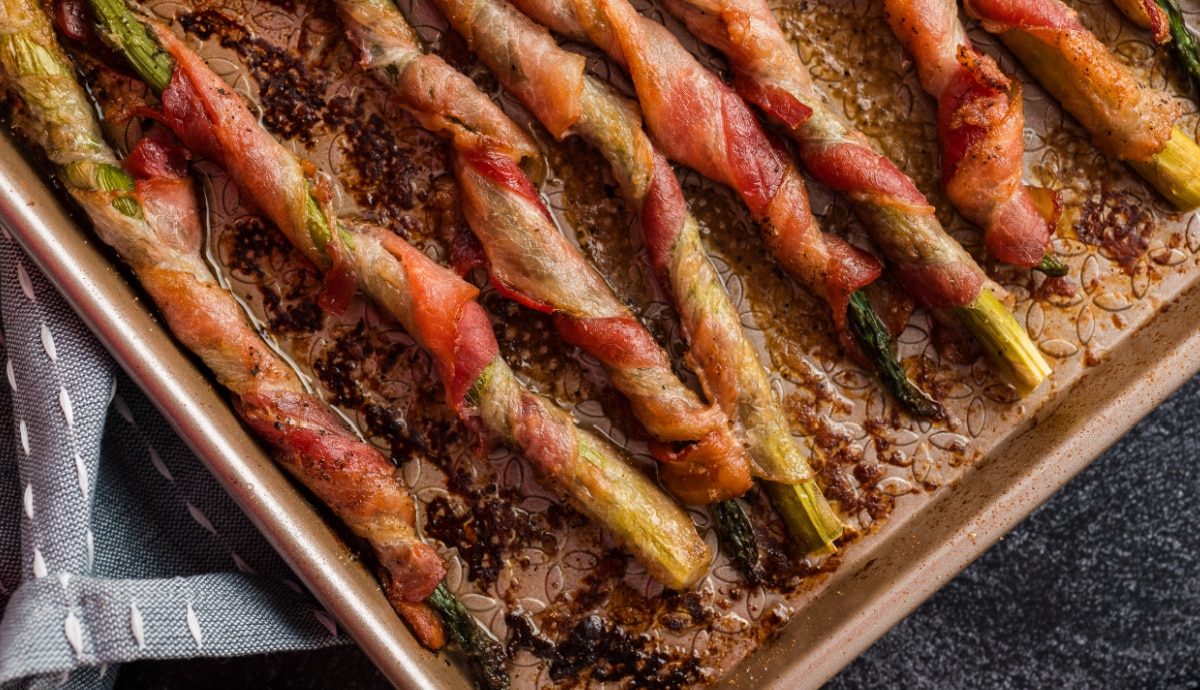 Overhead view of bacon-wrapped asparagus freshly roasted on a baking sheet