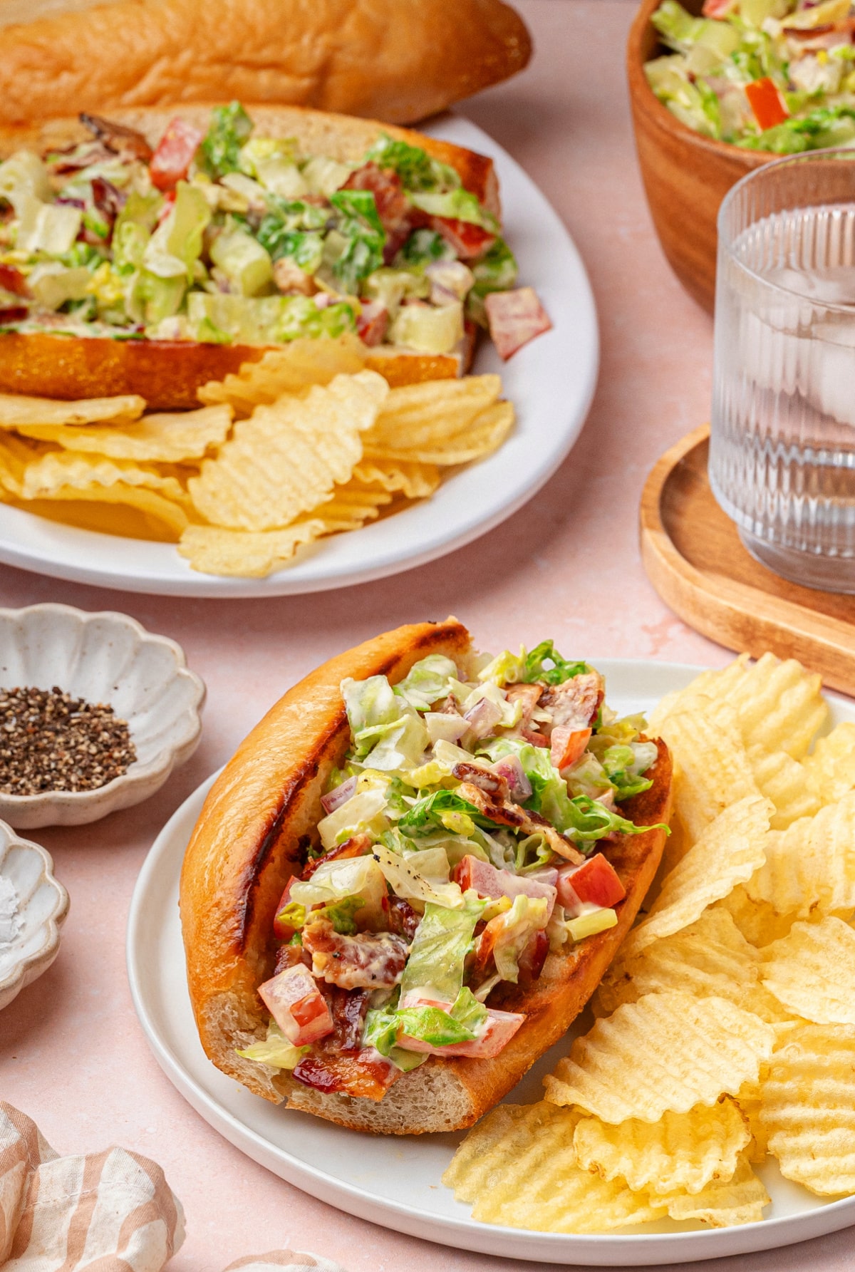 Chopped BLT hoagies served on plates with thick-cut potato chips on the side