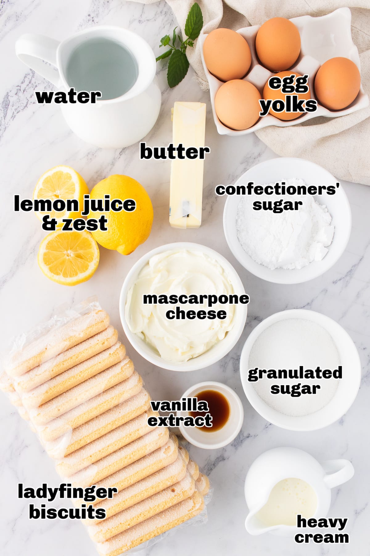 Ingredients laid out for lemon tiramisu, including mascarpone, lemons, and ladyfingers.