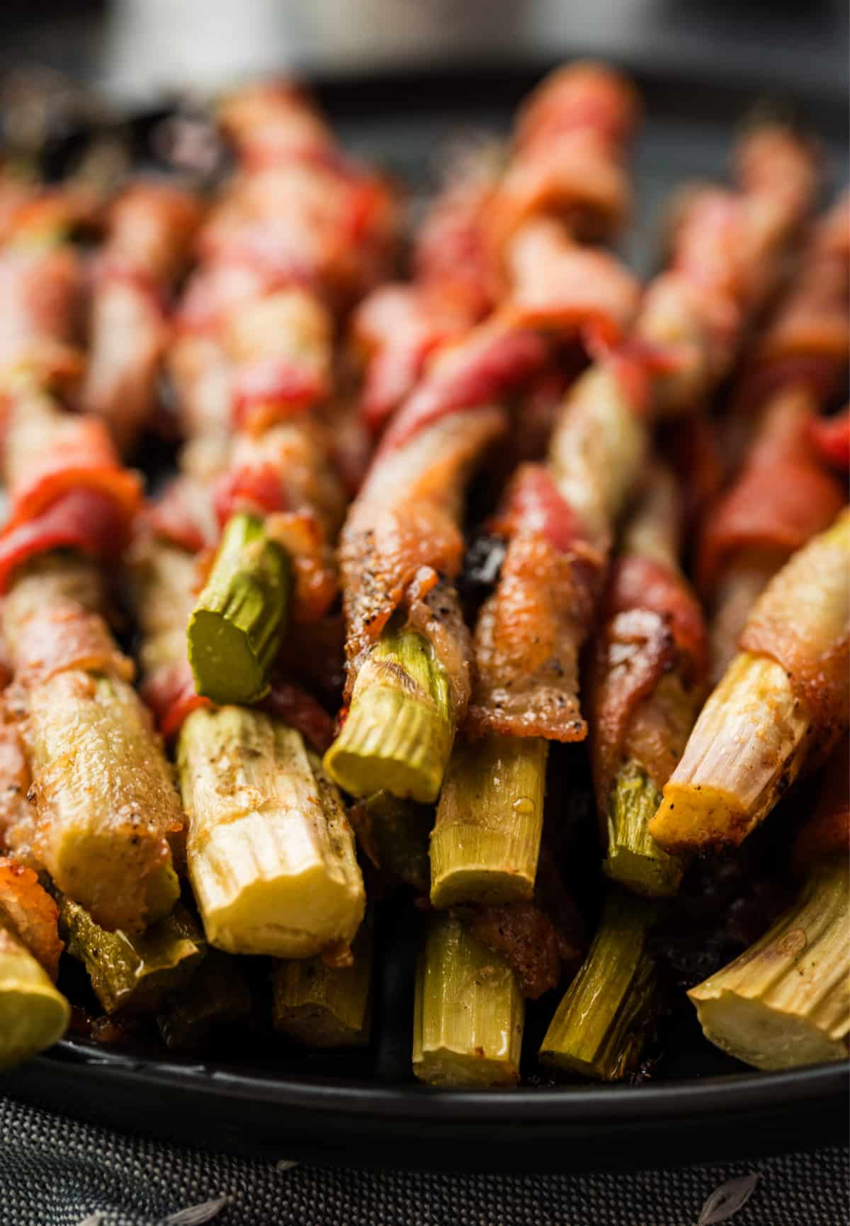 Bacon-wrapped asparagus on a serving platter with crisped ends visible