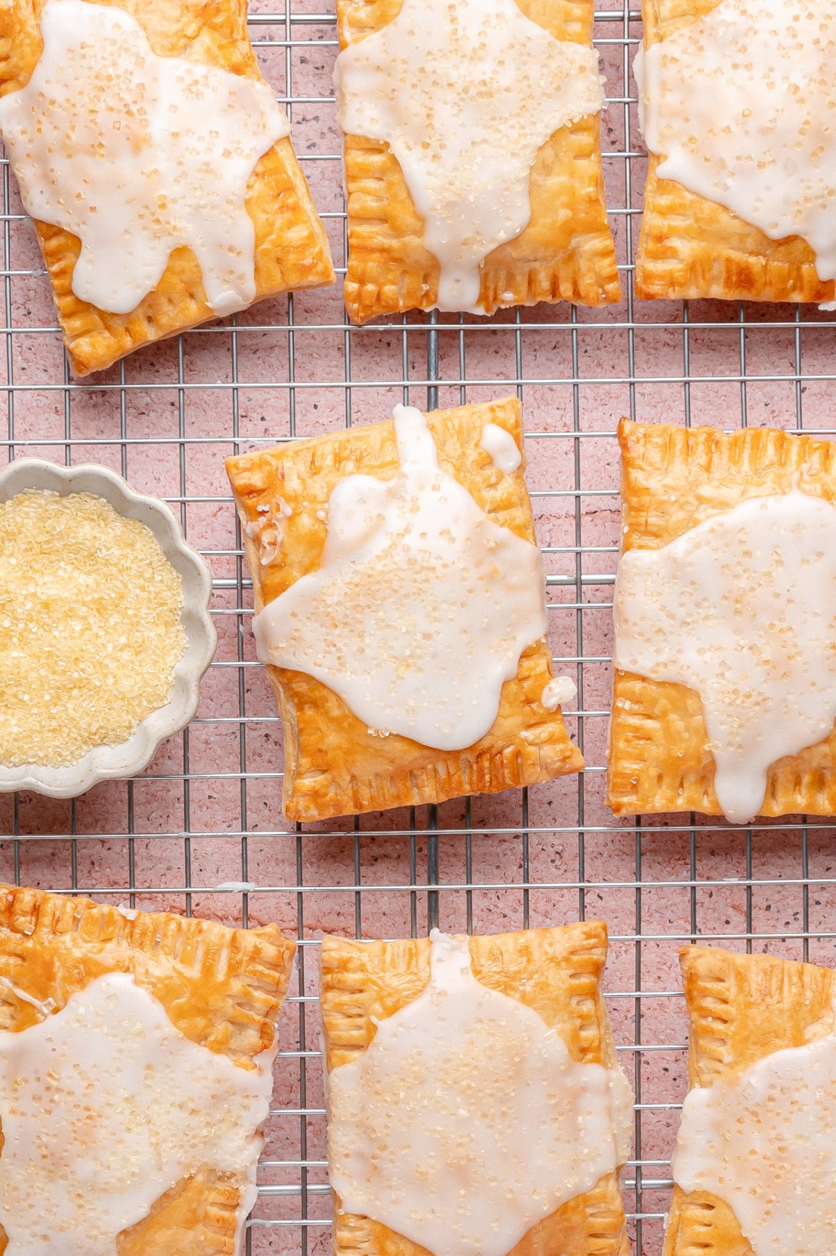 Homemade lemon pop tarts with glaze cooling on a wire rack, topped with coarse sugar sprinkles