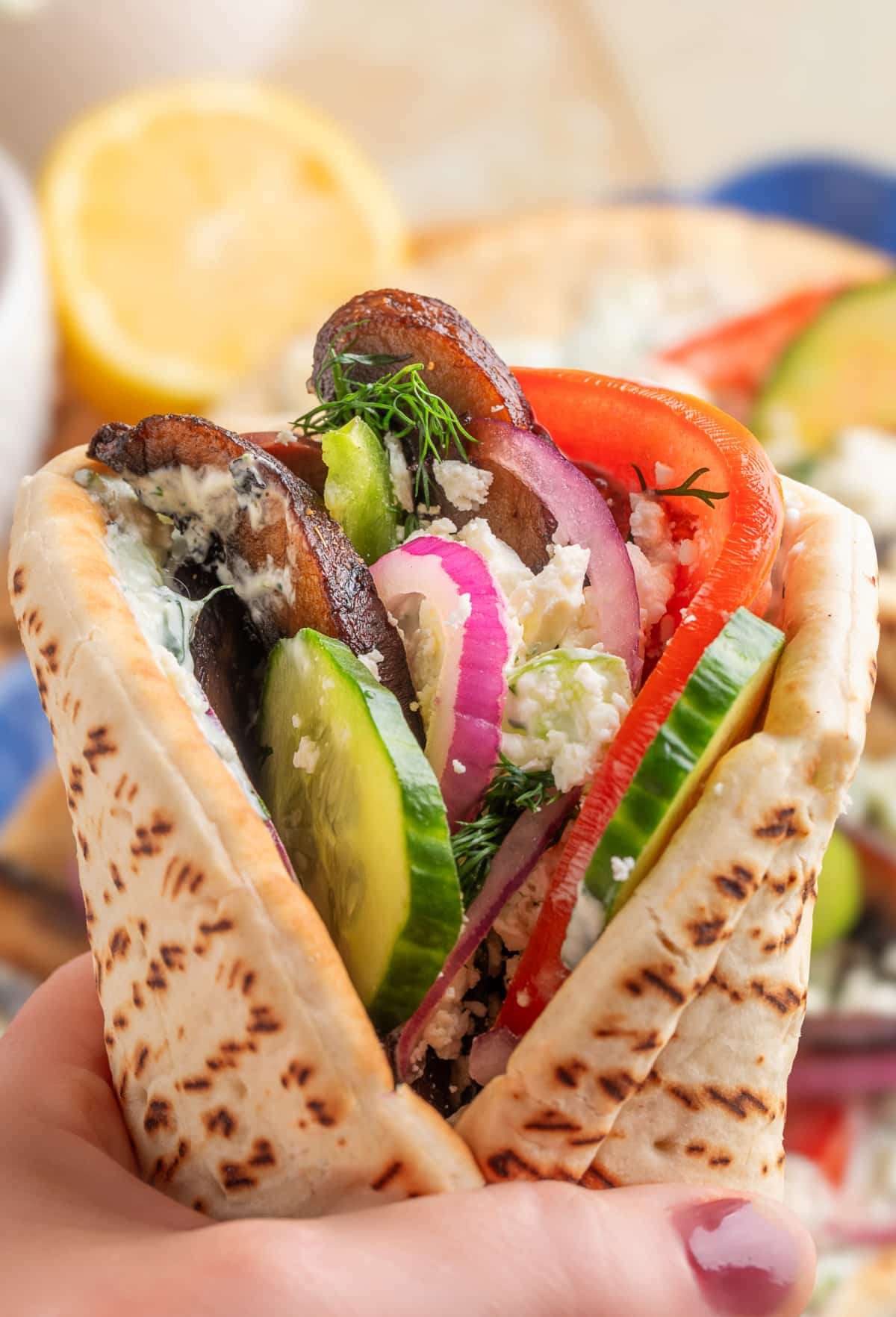 Hand holding a wrapped mushroom gyro Hand holding a finished portobello mushroom gyro, ready to eat.