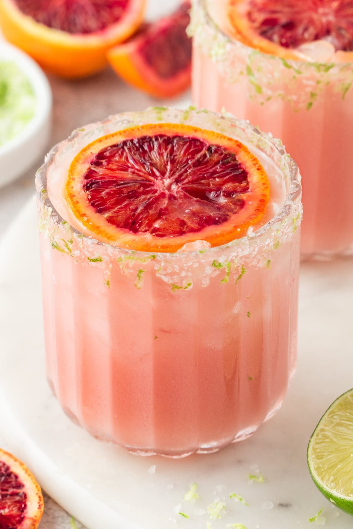 Citrus-Forward Blood Orange Coconut Margarita Vibrant blood orange margarita in a short glass, topped with a slice of blood orange and rimmed with salt and lime zest.