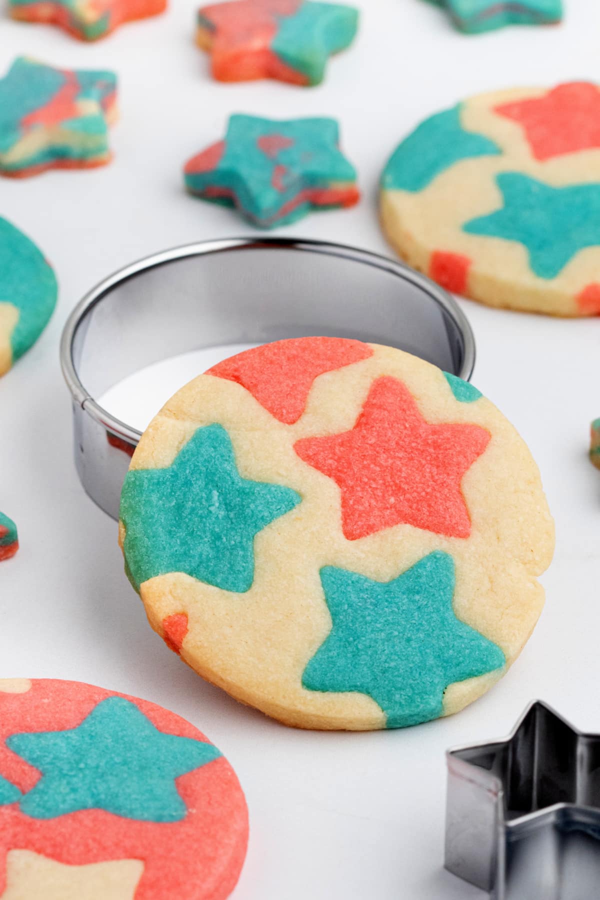 Red and blue star inlay cookie with round cutter on white surface Close-up of a patriotic round butter cookie with red and blue star inlays, sitting in a metal cookie cutter