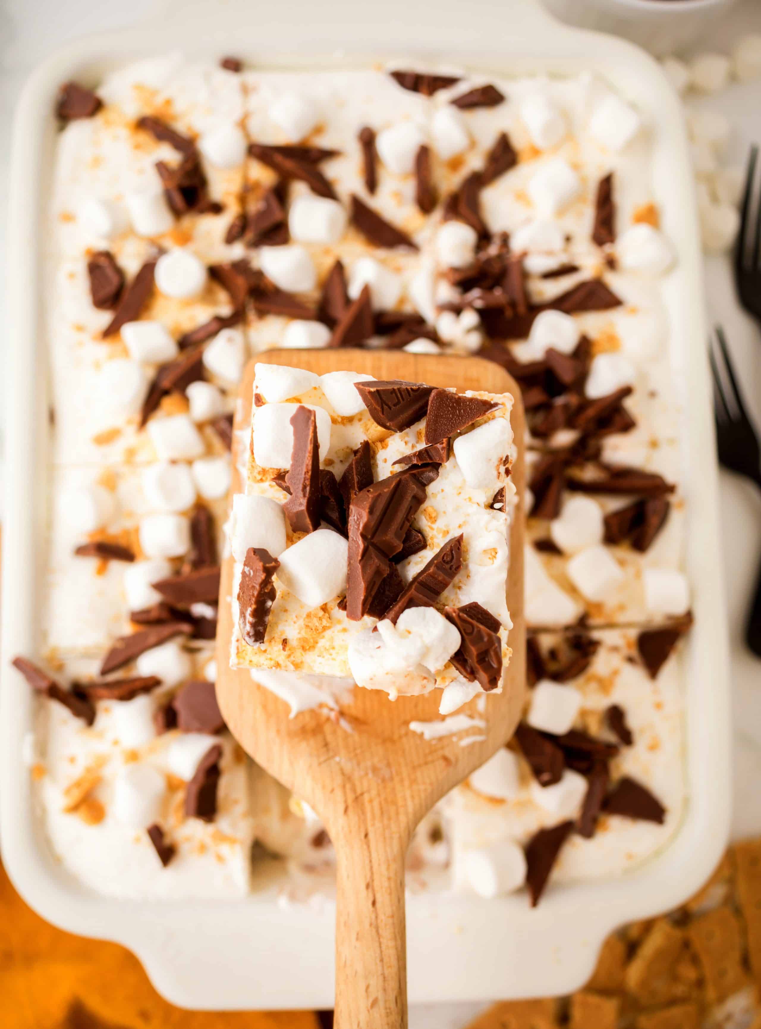 Frozen s’mores lasagna slice topped with mini marshmallows and Hershey’s chocolate
