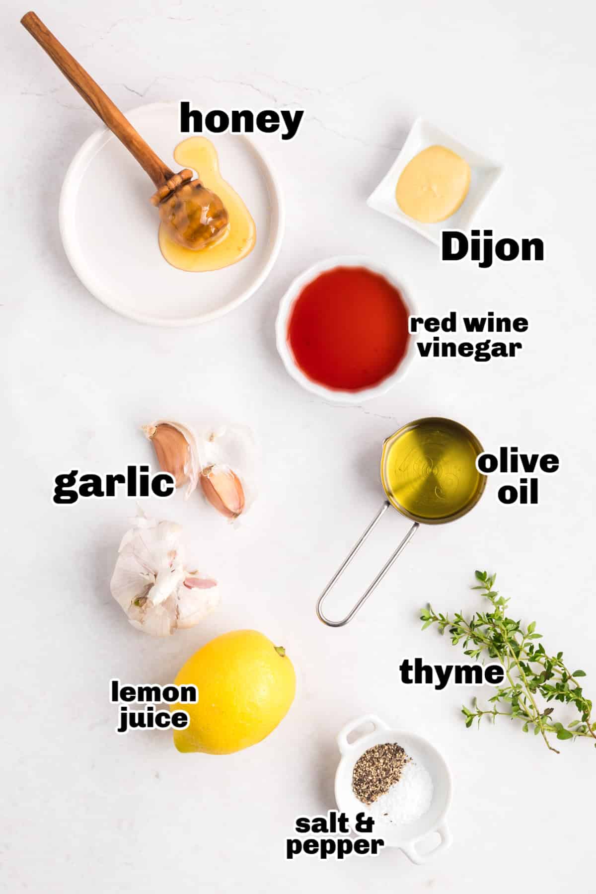 Overhead view of ingredients for honey Dijon dressing labeled and arranged on white surface
