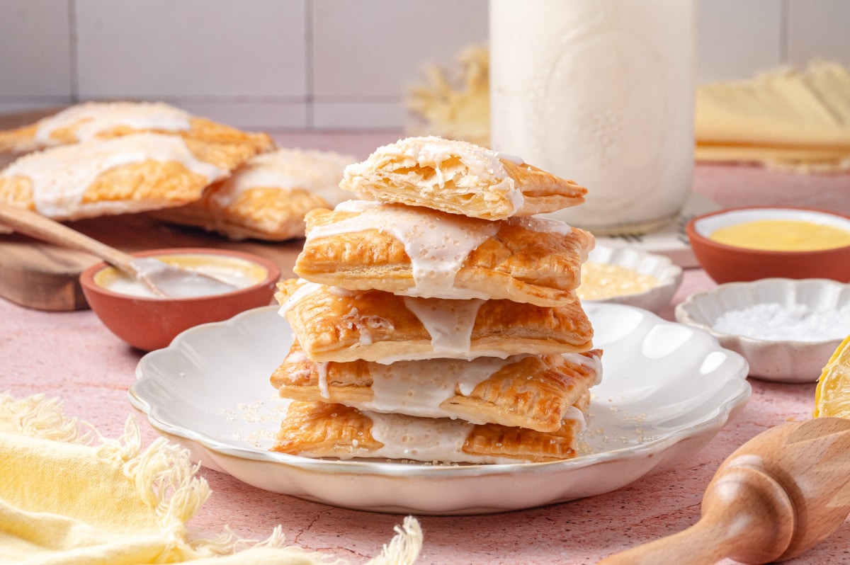 Stack of flaky lemon toaster pastries with a bite showing the lemon curd filling