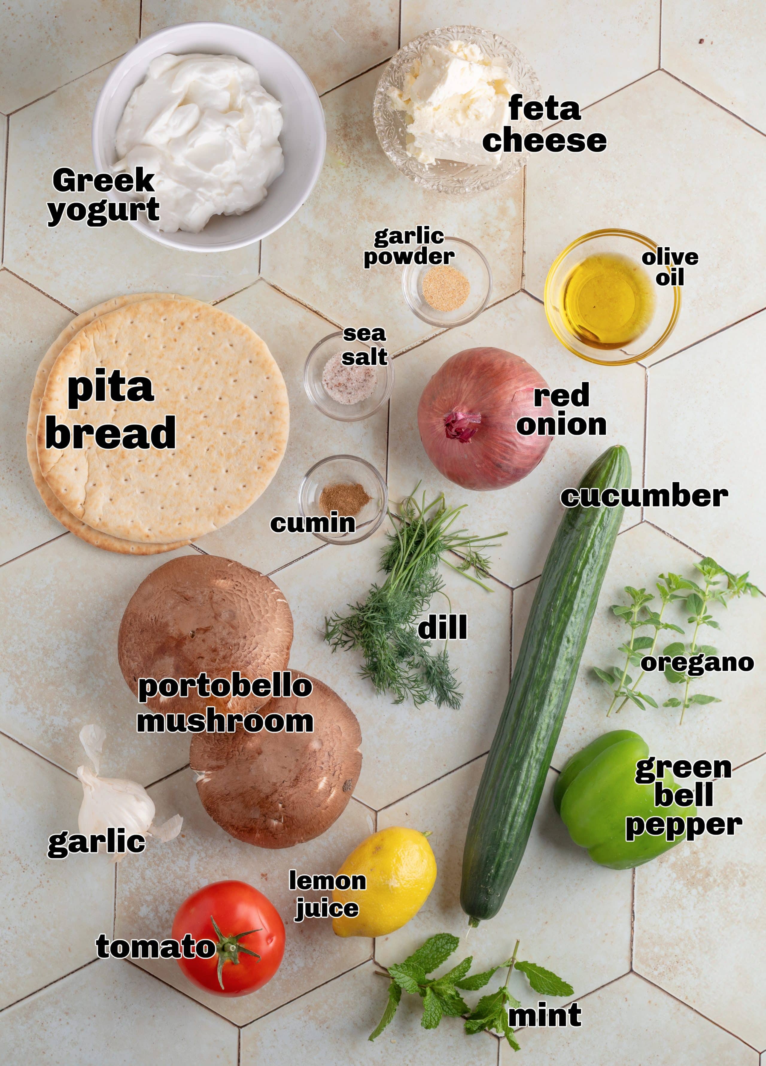 Ingredients for mushroom gyros with tzatziki Ingredients for portobello mushroom gyros laid out on a white surface.