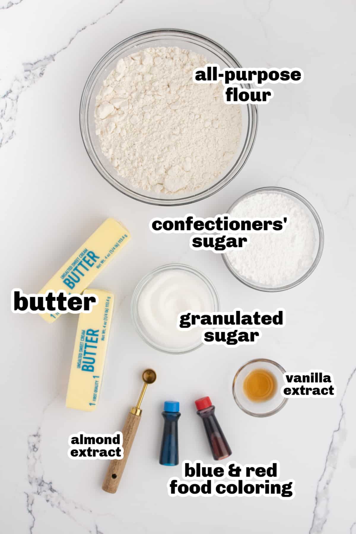 Ingredients for red, white, and blue butter cookies laid out on counter Overhead view of labeled ingredients for butter cookies, including flour, sugars, butter, extracts, and food coloring