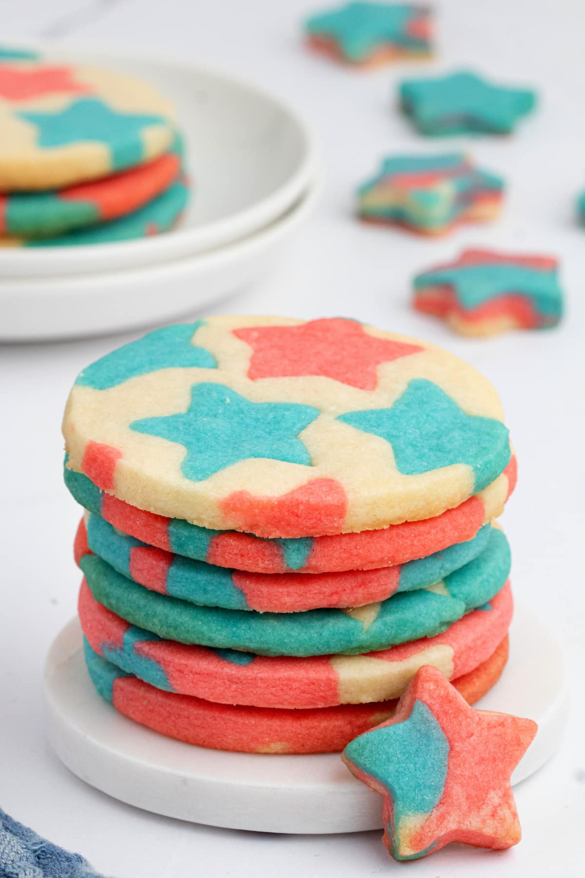Stacked patriotic butter cookies with inlay star pattern and marbled mini cookie Stack of red, white, and blue butter cookies with colorful star patterns, with a marbled mini star cookie in front