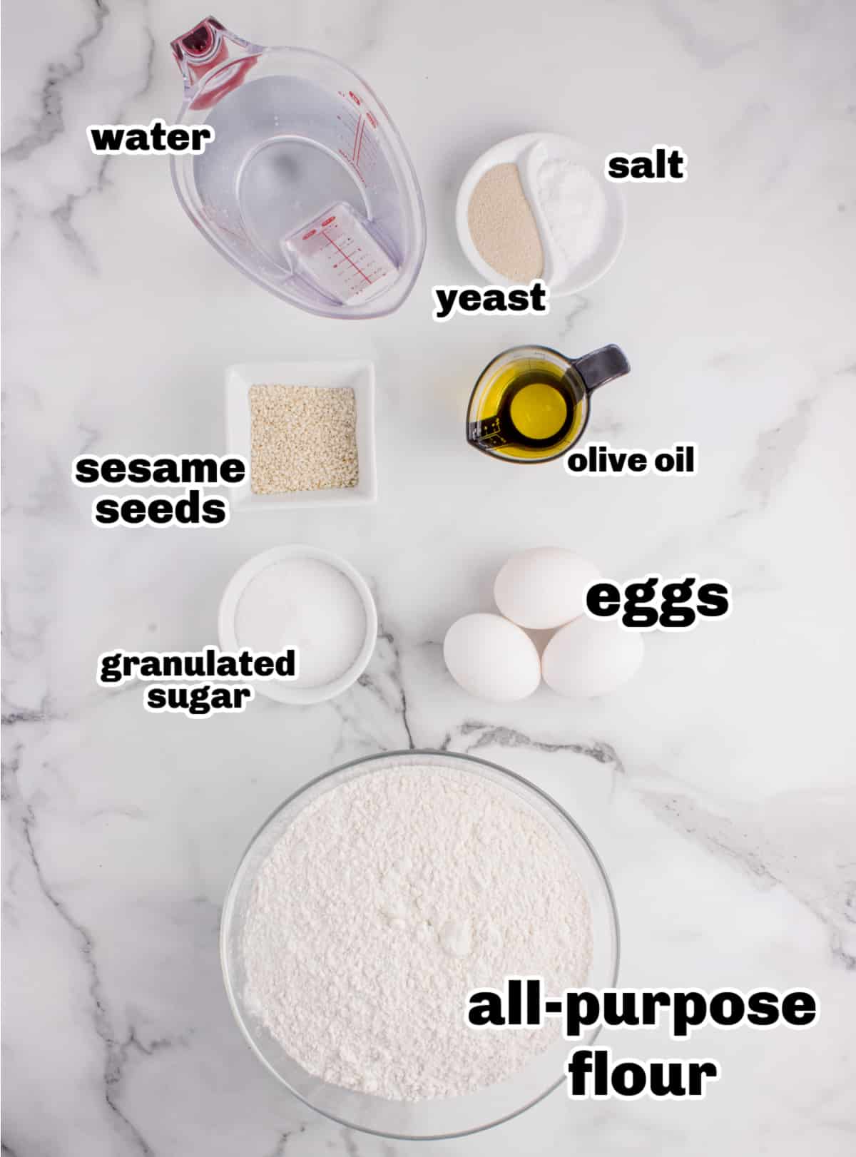 Ingredients needed to make homemade challah bread Overhead of measured ingredients for challah bread including flour, eggs, oil, sugar, and sesame