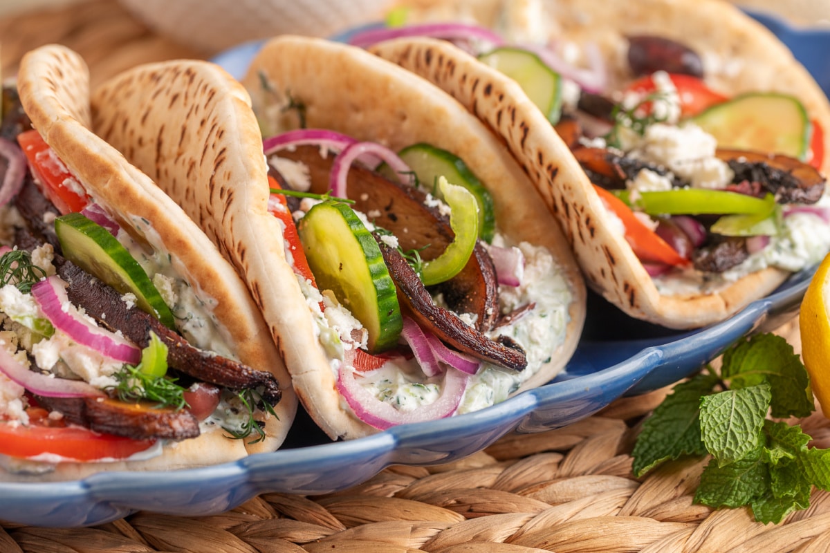 Portobello mushroom gyros arranged on a blue serving platter. Portobello Mushroom Gyros with Tzatziki and Feta