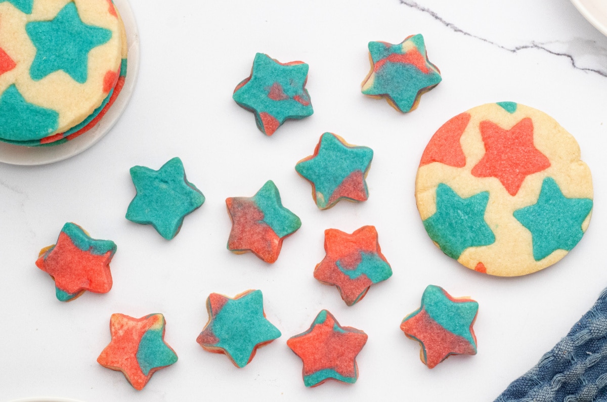 Mini marbled patriotic star cookies and one round inlay cookie on white surface Assortment of small marbled star cookies arranged next to a large round star-patterned cookie
