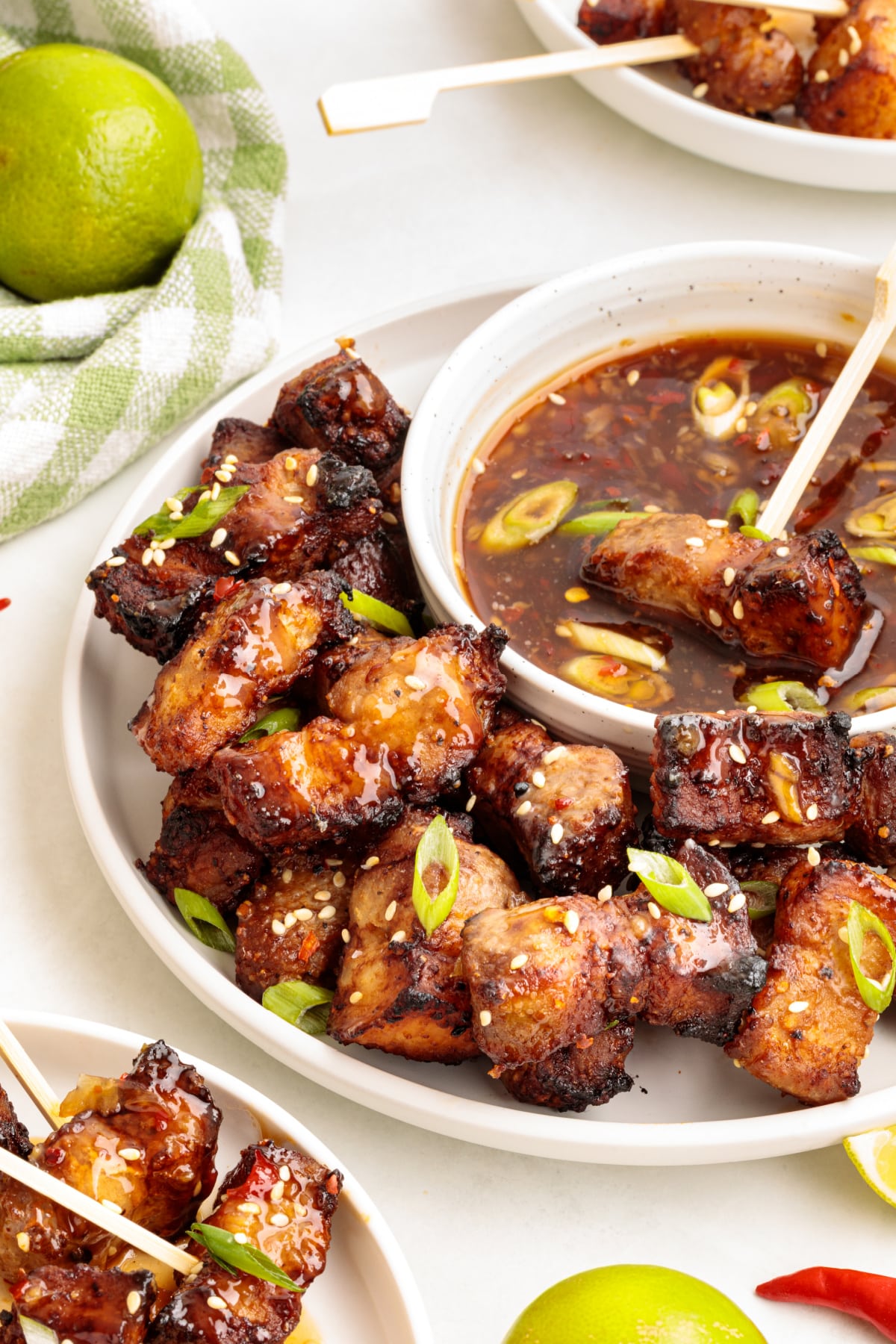 Overhead shot of crispy air fryer pork belly cubes served with Thai sweet chili lime dipping sauce, garnished with sesame seeds and scallions.