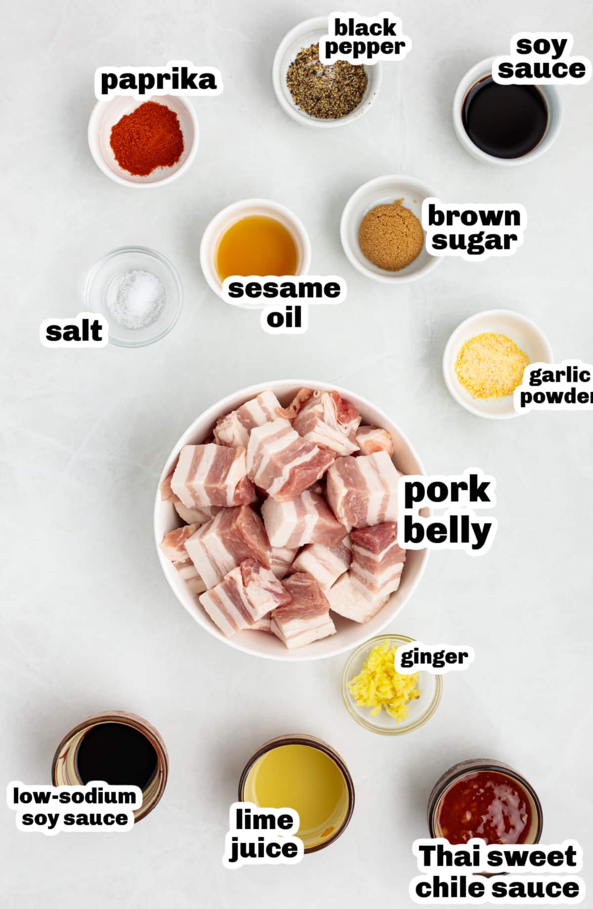 Flat lay of pork belly bite ingredients including brown sugar, soy sauce, sesame oil, garlic powder, paprika, and sweet chili sauce.