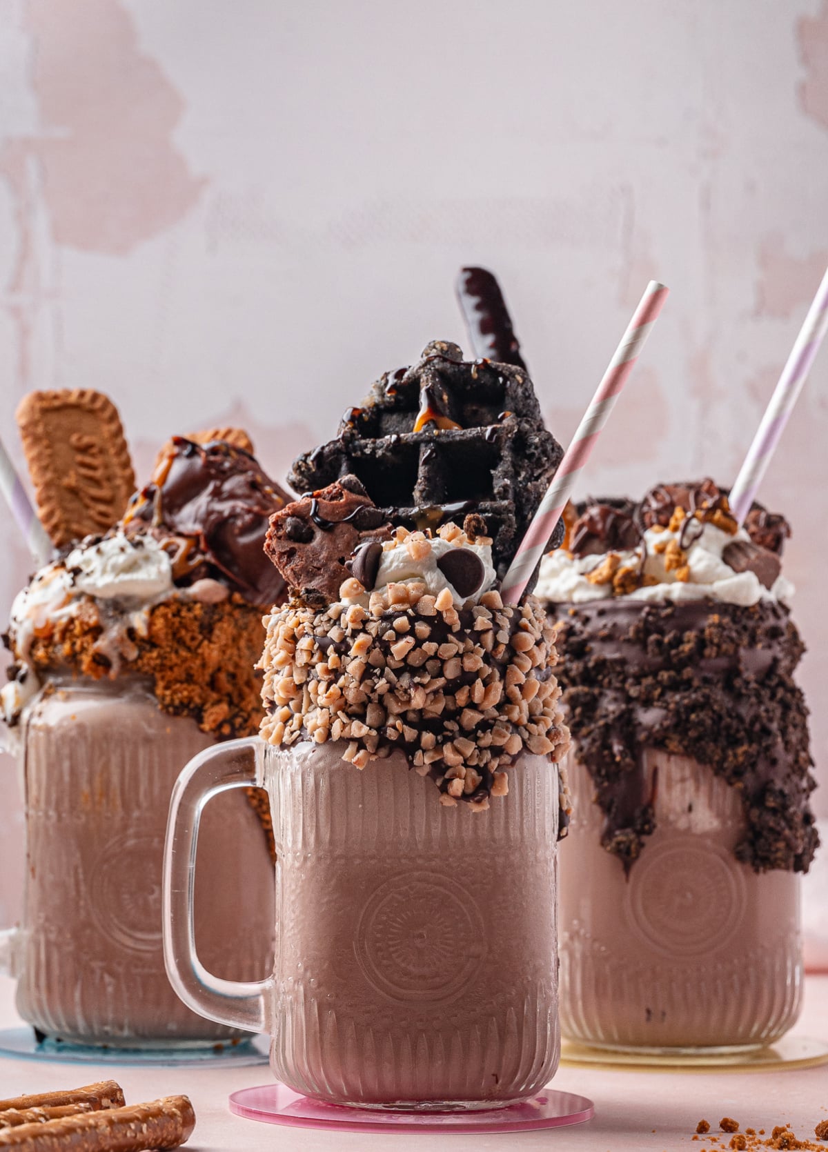 Extreme milkshakes with cookie crusted rims and stacked toppings Three chocolate freakshakes with decorated rims and dramatic candy and dessert toppings