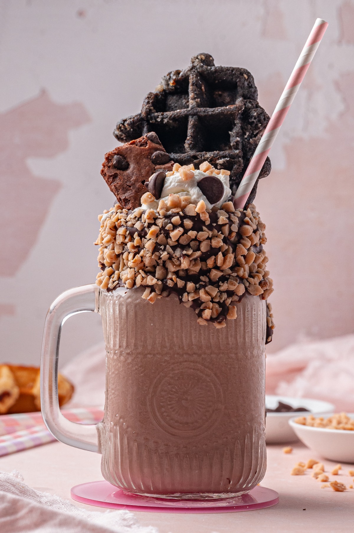 Loaded chocolate milkshake with toffee bits and chocolate waffle Close-up of a chocolate freakshake with crushed toffee rim, whipped cream, brownie, and waffle