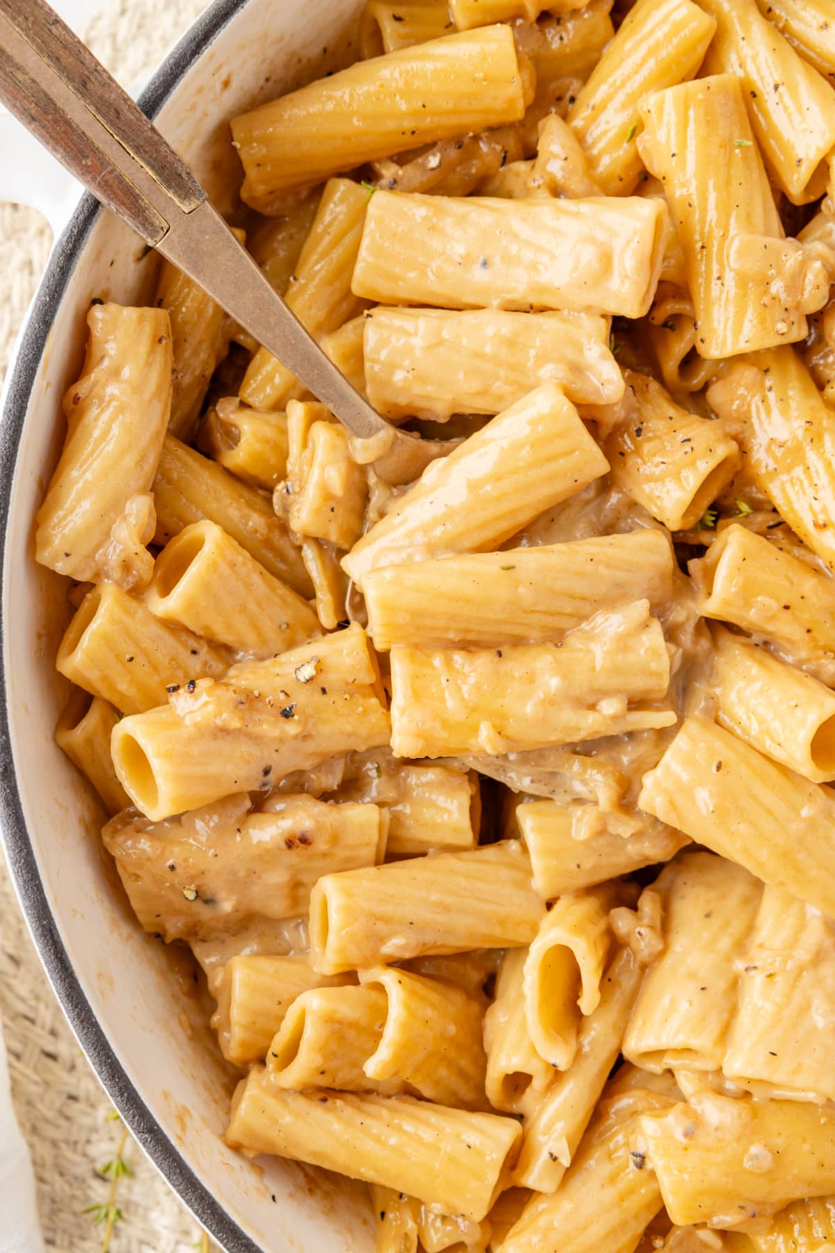 Simple French onion pasta cooked in one pan Rigatoni pasta coated in golden onion cream sauce served in a white Dutch oven.