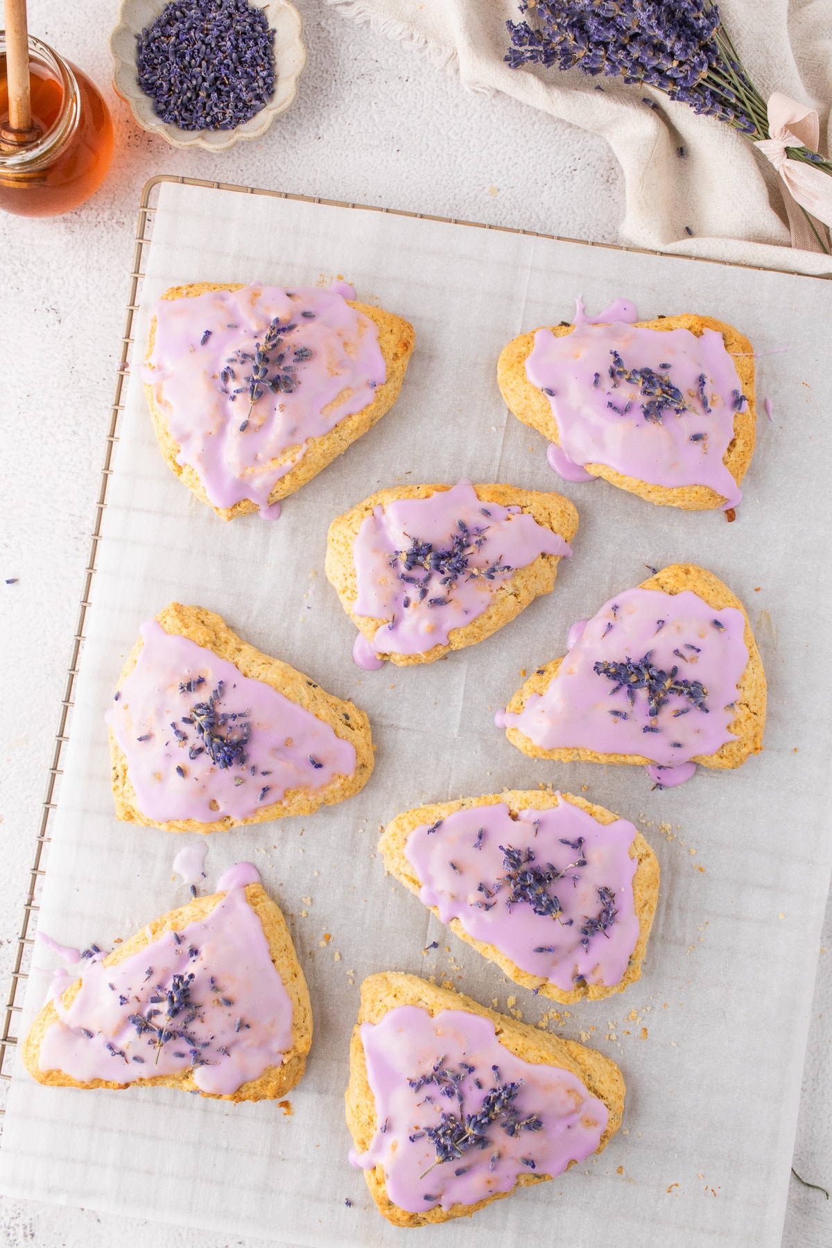Baked lavender scones with honey and floral glaze cooling on parchment Freshly baked honey lavender scones topped with a natural purple glaze and dried lavender