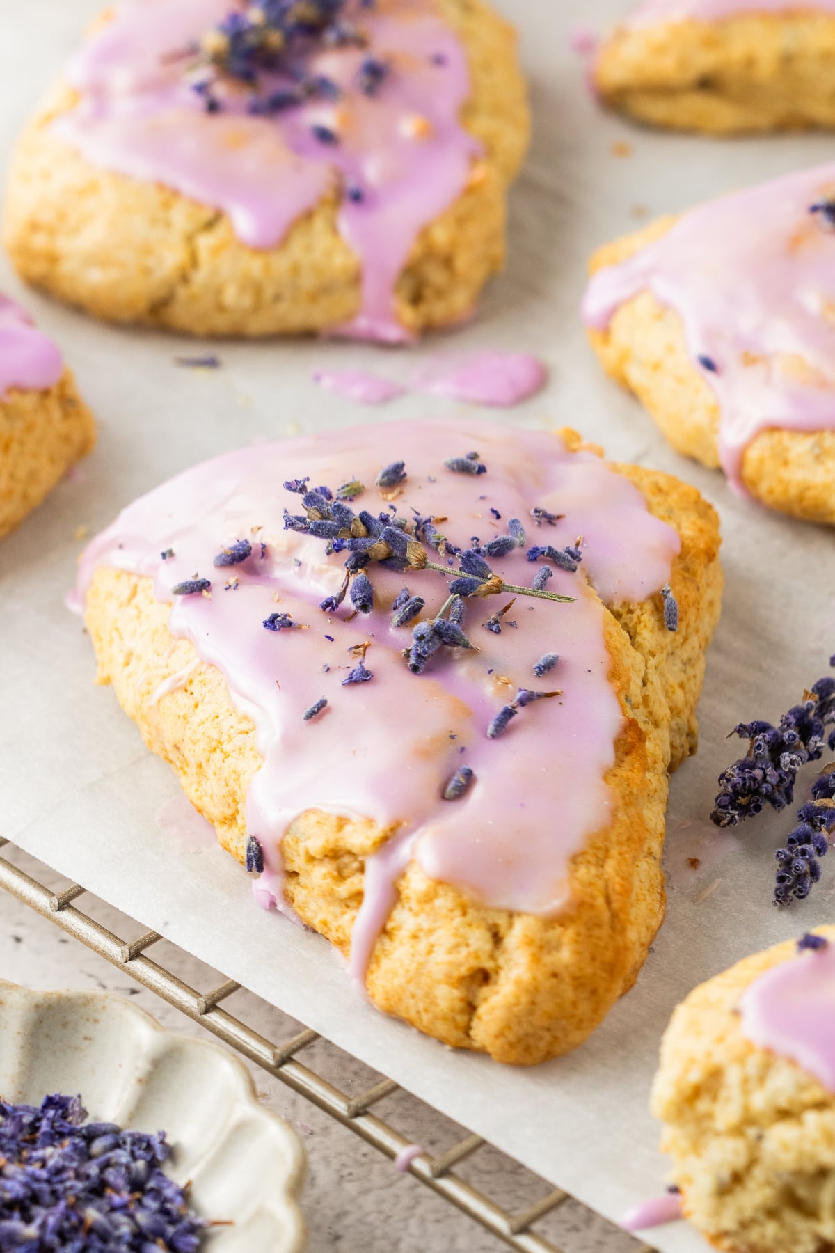 Close-up of glazed lavender scone perfect for brunch or tea time Soft honey lavender scone with purple glaze and dried lavender garnish, close-up on a wire rack