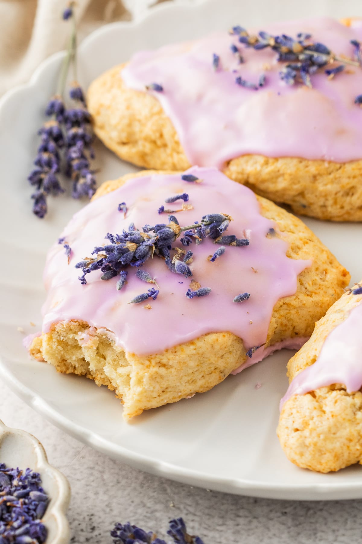 Honey lavender scone with floral glaze and soft interior texture Lavender scone with a bite taken out, showing soft, tender texture and glossy glaze
