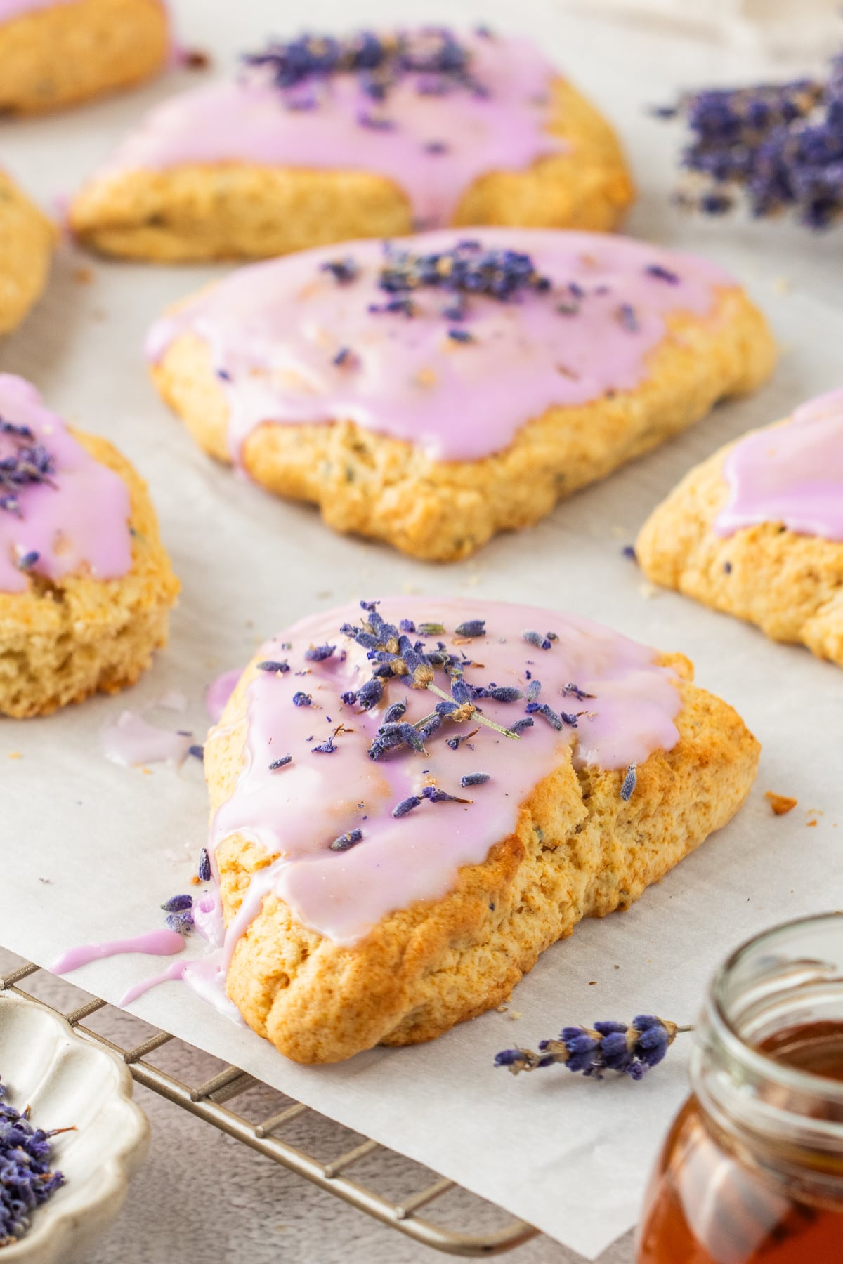 Simple homemade lavender scones with natural glaze for brunch or tea Honey lavender scones arranged on a baking rack with drizzled berry glaze and lavender