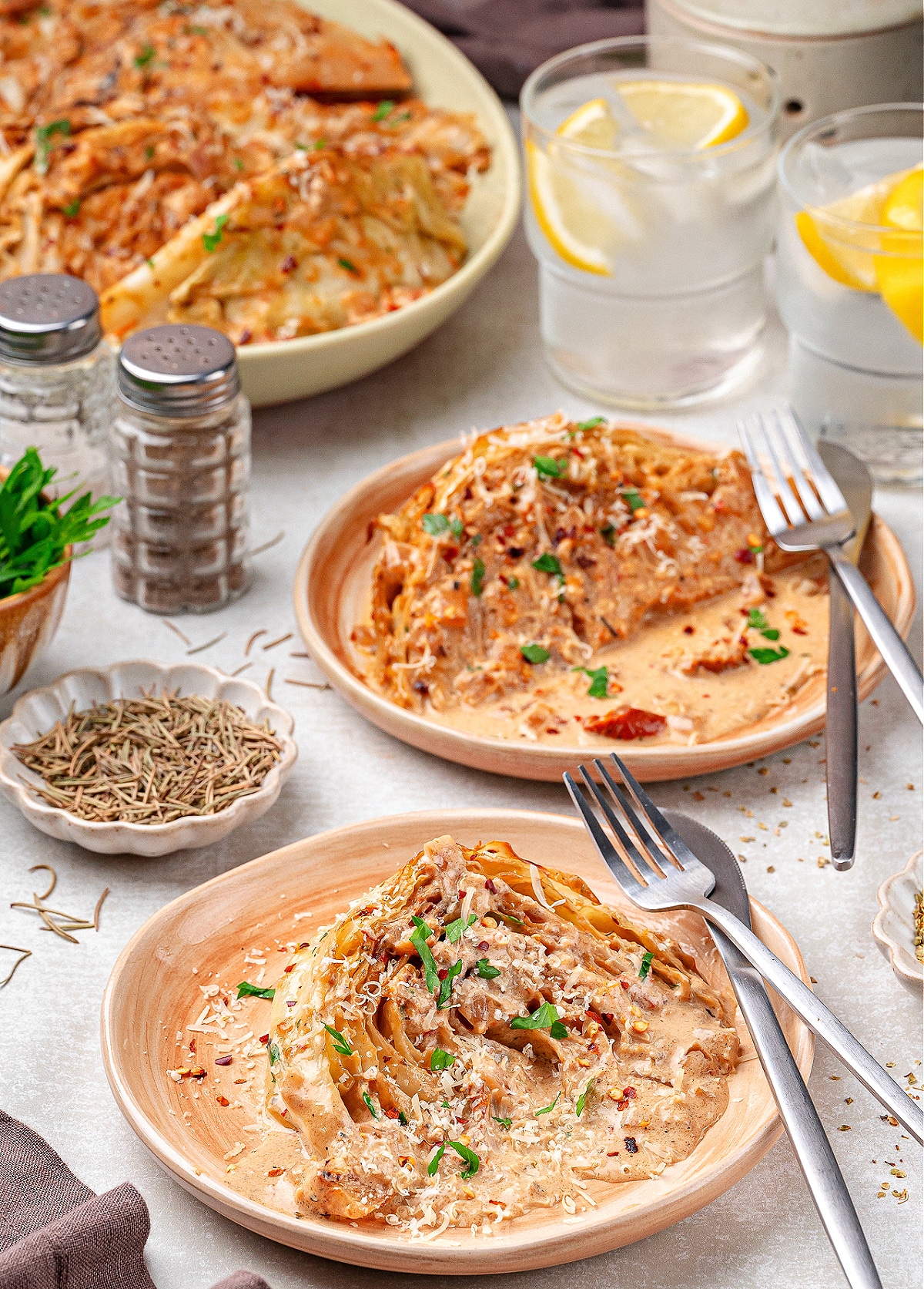 Cabbage in cream sauce served on plates with fresh parsley and red pepper flakes, perfect as a comforting cabbage dinner.