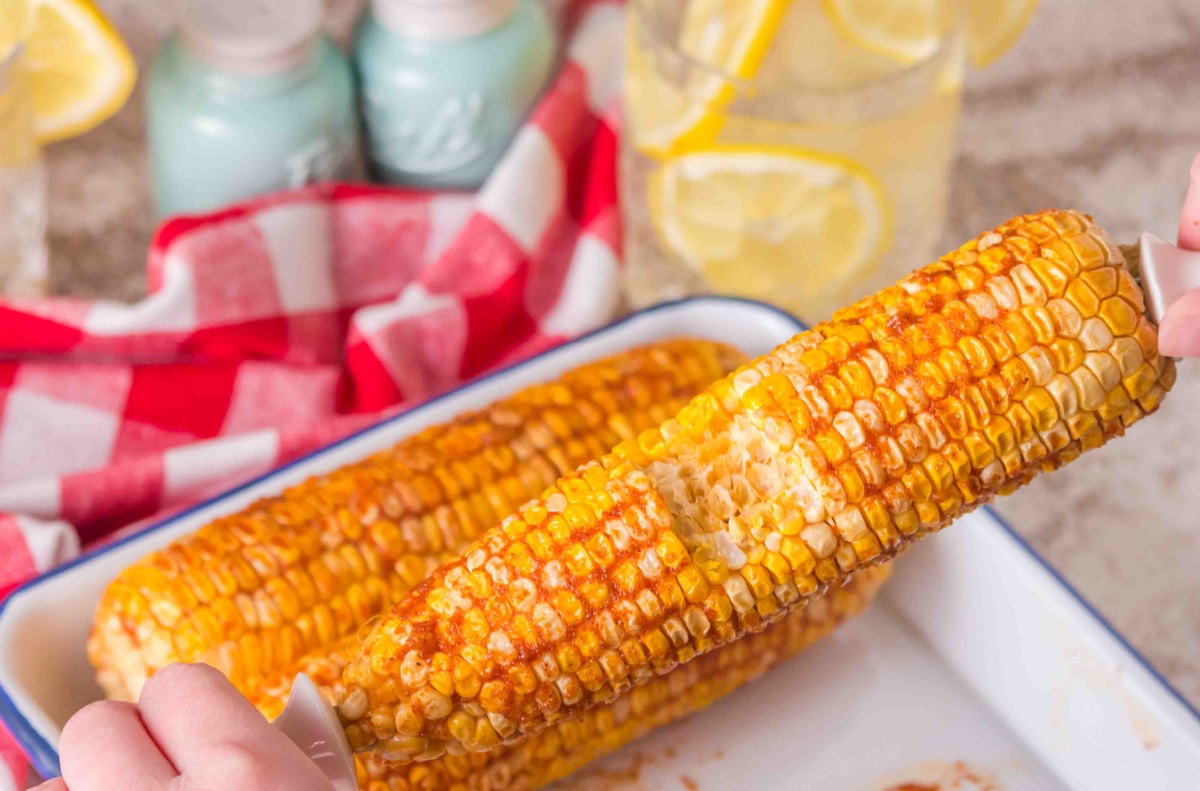 Smoked corn on the cob with seasoned butter after grilling Smoked corn on the cob with bite taken, served with garlic butter and paprika