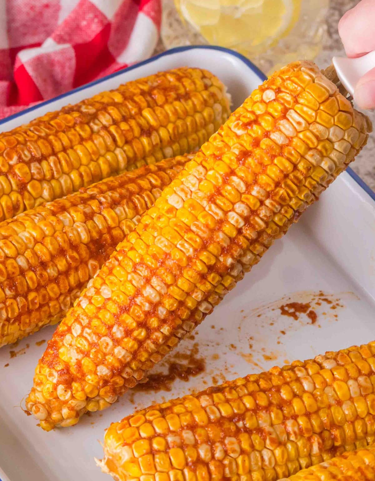 Smoked corn on the cob straight off the pellet grill with seasoned butter Freshly smoked corn on the cob with brown sugar garlic butter on white tray