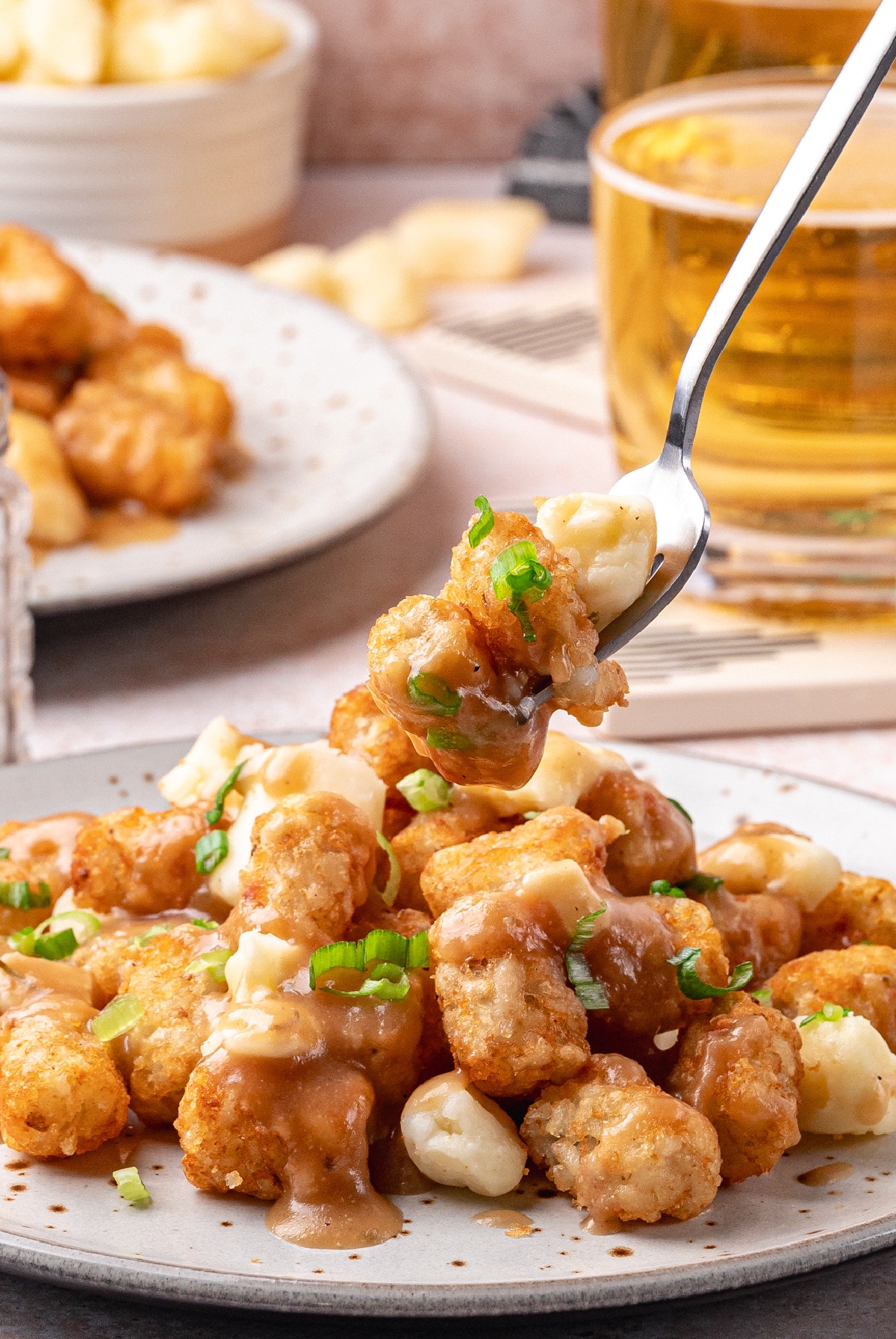 Crispy Tater Tot Poutine with Gravy and Cheese Curds – Easy Appetizer Recipe Close-up of crispy tater tot poutine with cheese curds, green onions, and thick homemade gravy on a plate.