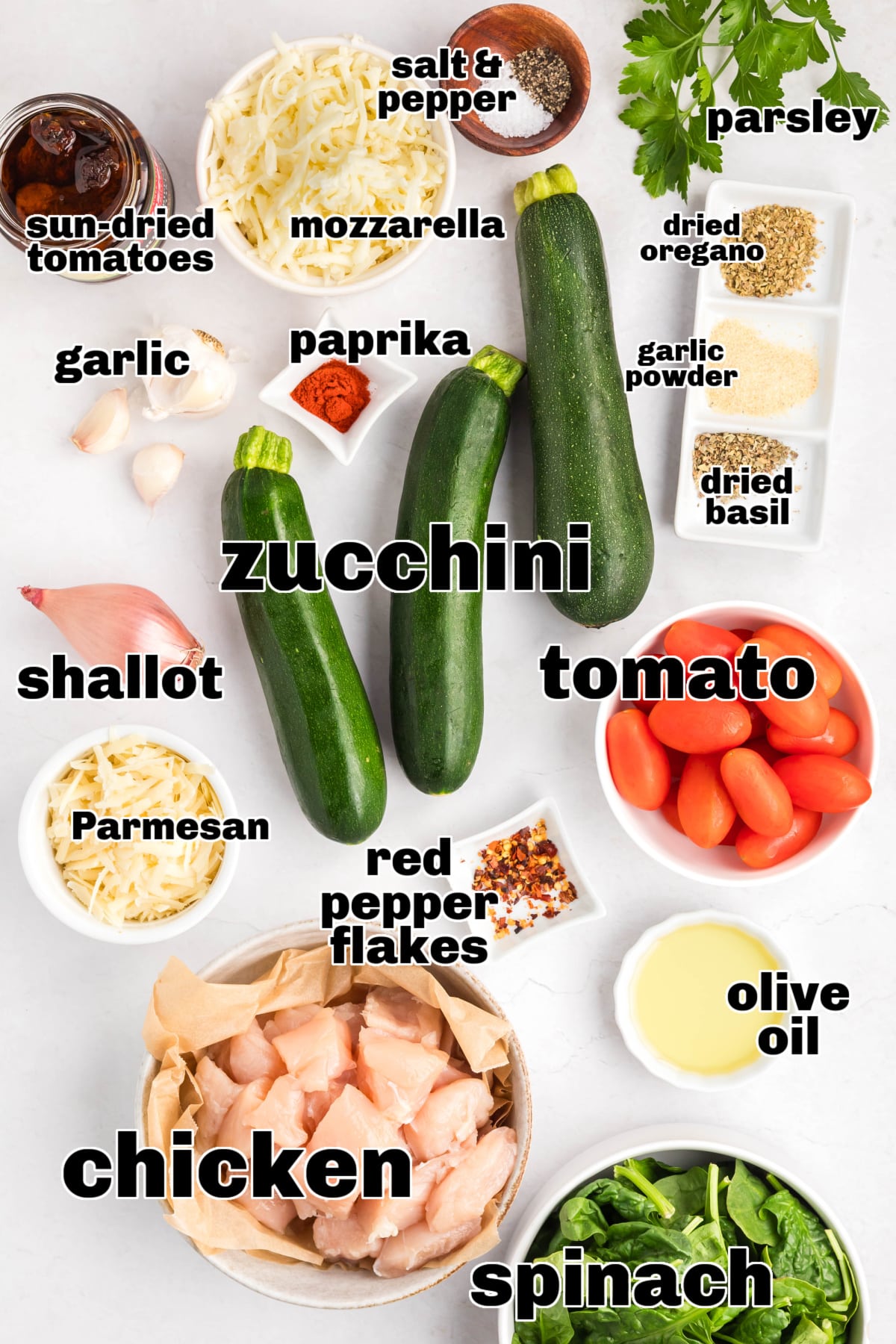 Ingredients for Chicken Zucchini Casserole with Herbs and Cheese Flat lay of ingredients for Tuscan chicken zucchini casserole including raw chicken, zucchini, tomatoes, and shredded cheese.