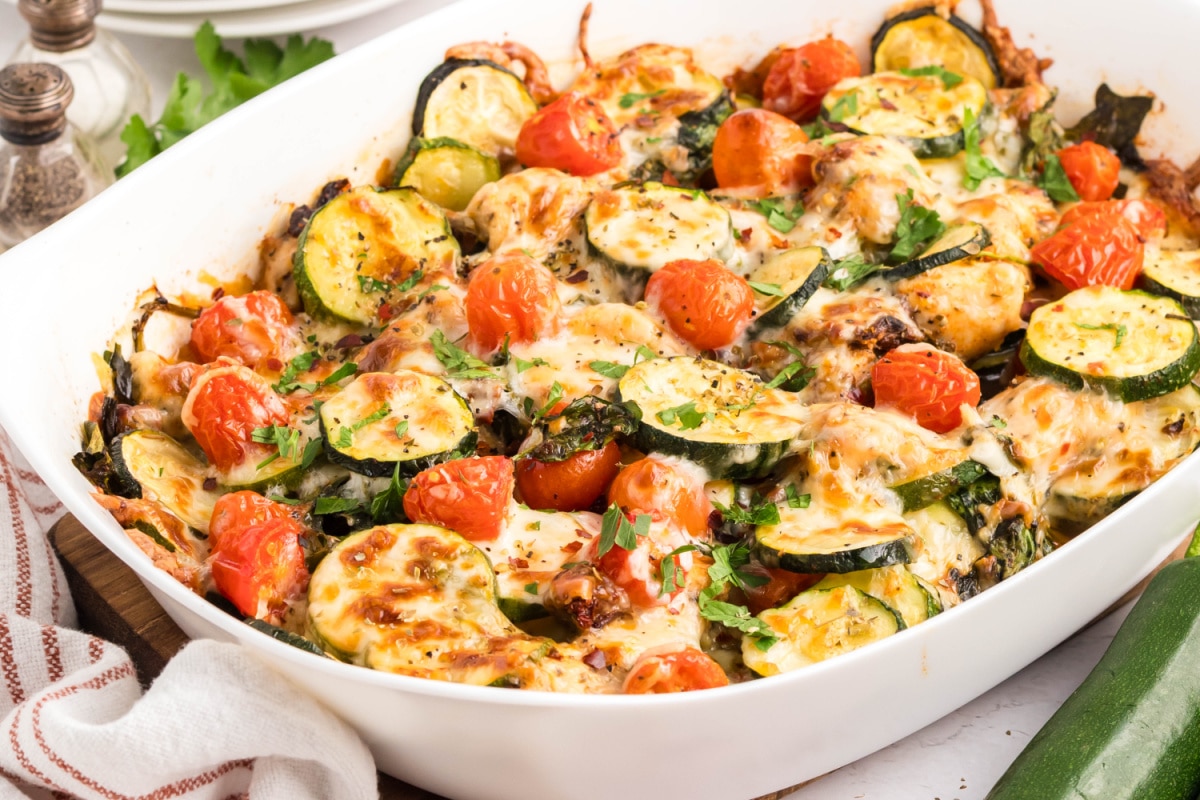 Mediterranean-Inspired Chicken Zucchini Bake with Golden Cheese Close-up of melted cheese, zucchini slices, and tomatoes in Tuscan-style chicken casserole topped with parsley.