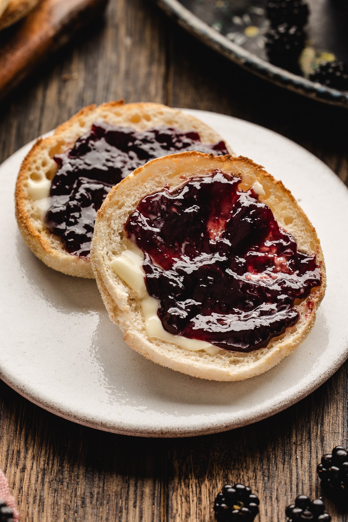 Toasted English muffins topped with glossy homemade blackberry jam and butter
