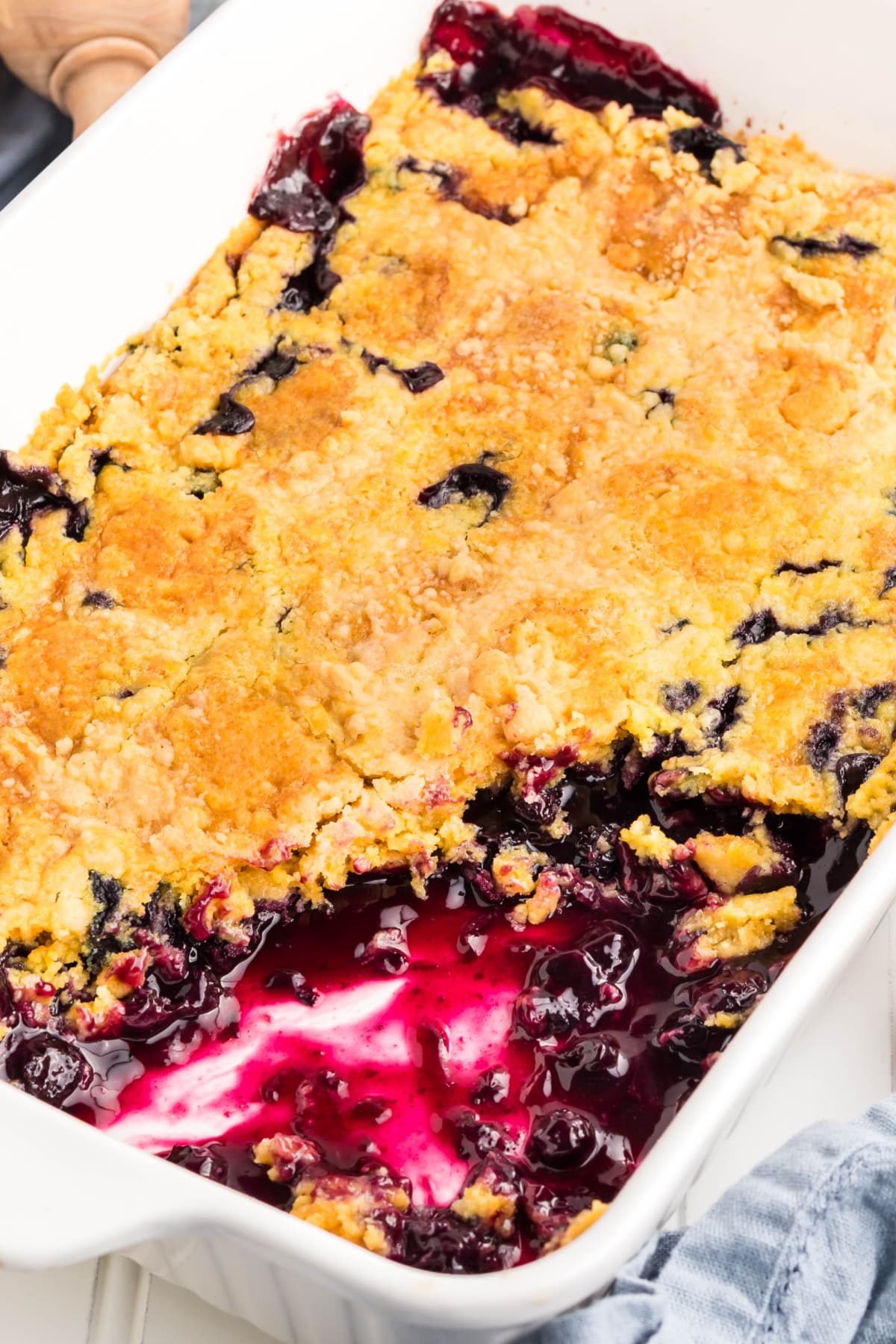 Blueberry dump cake with golden crust and bubbling filling in a white dish.