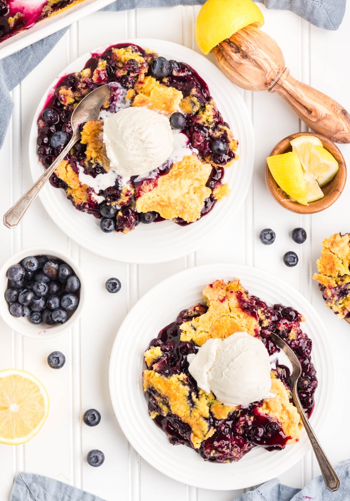 Two plates of lemon blueberry dessert with scoops of ice cream.