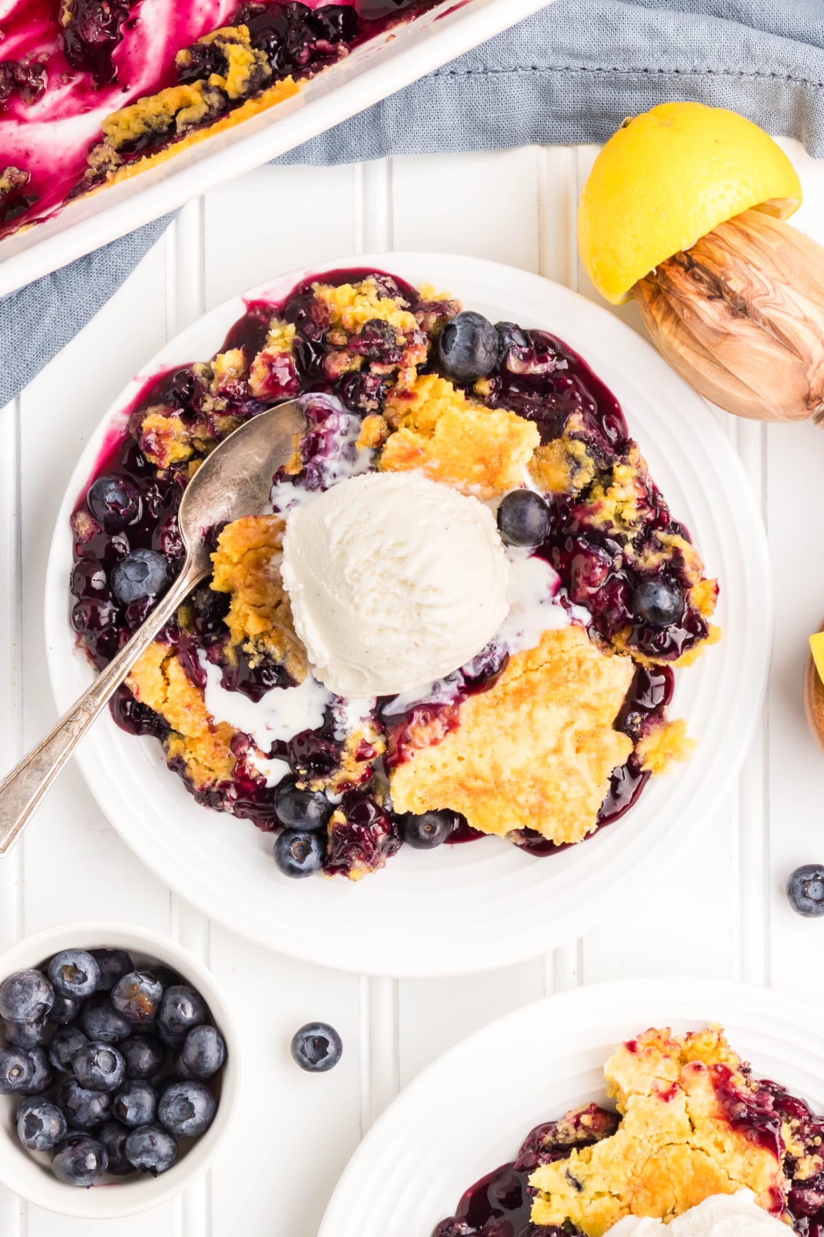 Overhead view of blueberry dump cake served with vanilla ice cream and fresh blueberries.