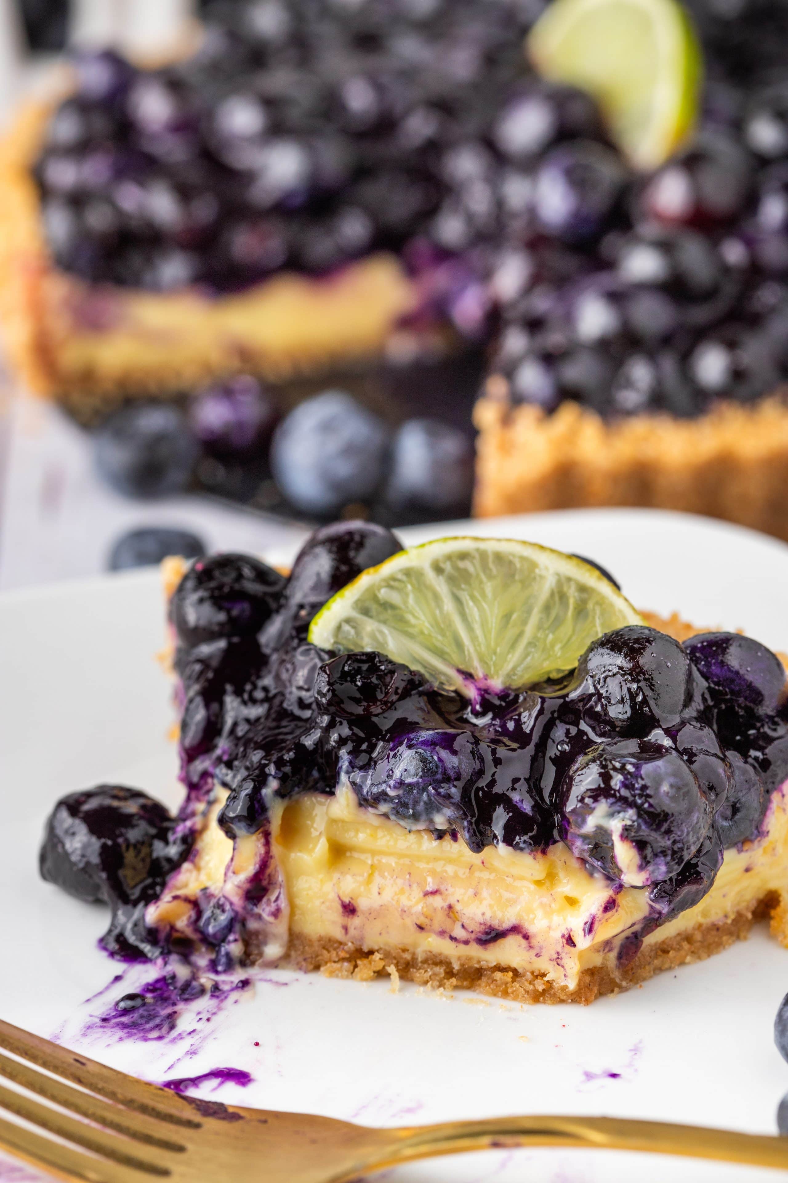 Blueberry Key Lime Tart Blueberry Lime Tart slice topped with blueberries and lime.
