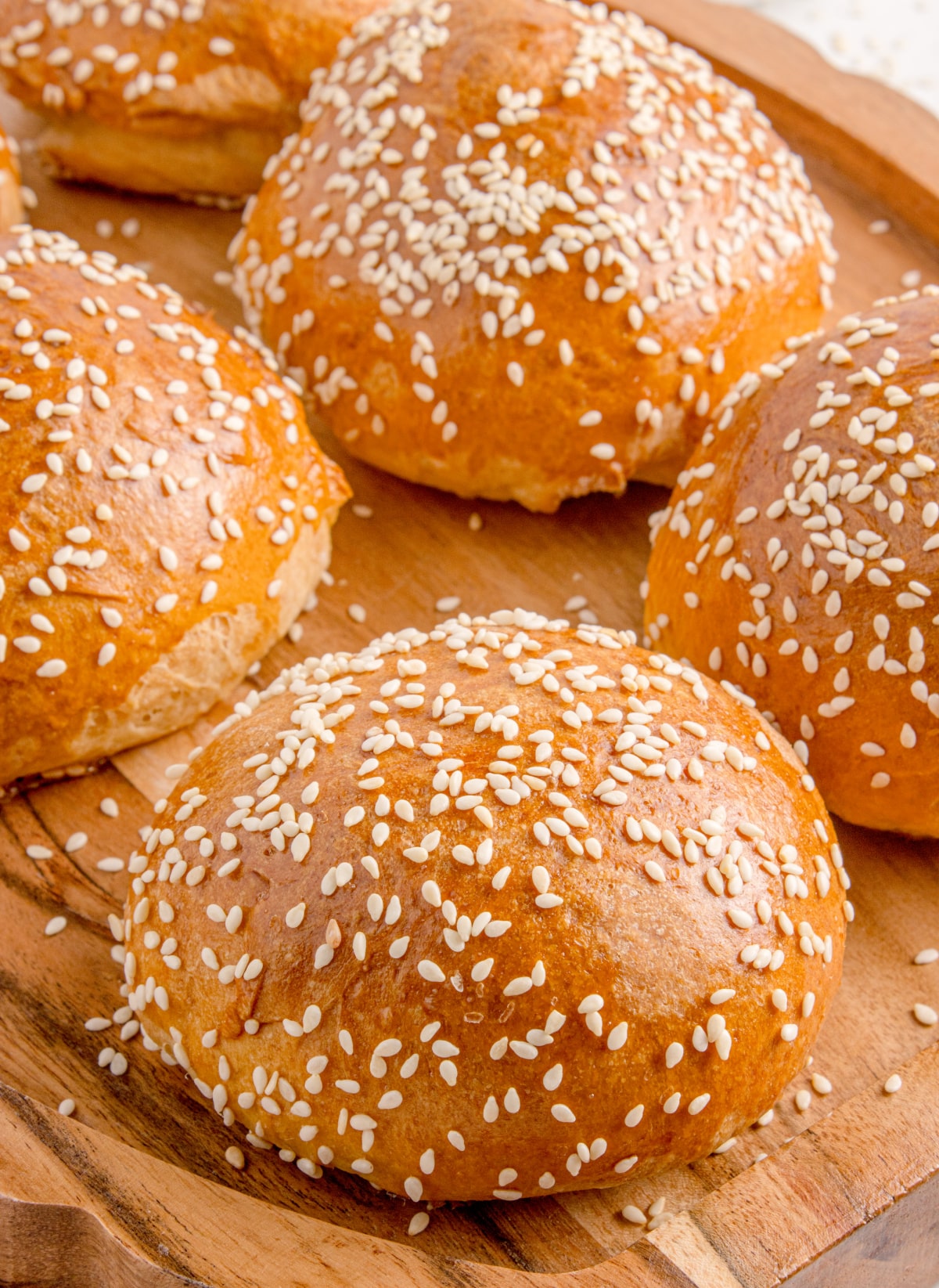 Freshly baked sesame slider buns Golden baked slider buns topped with sesame seeds on a wooden board