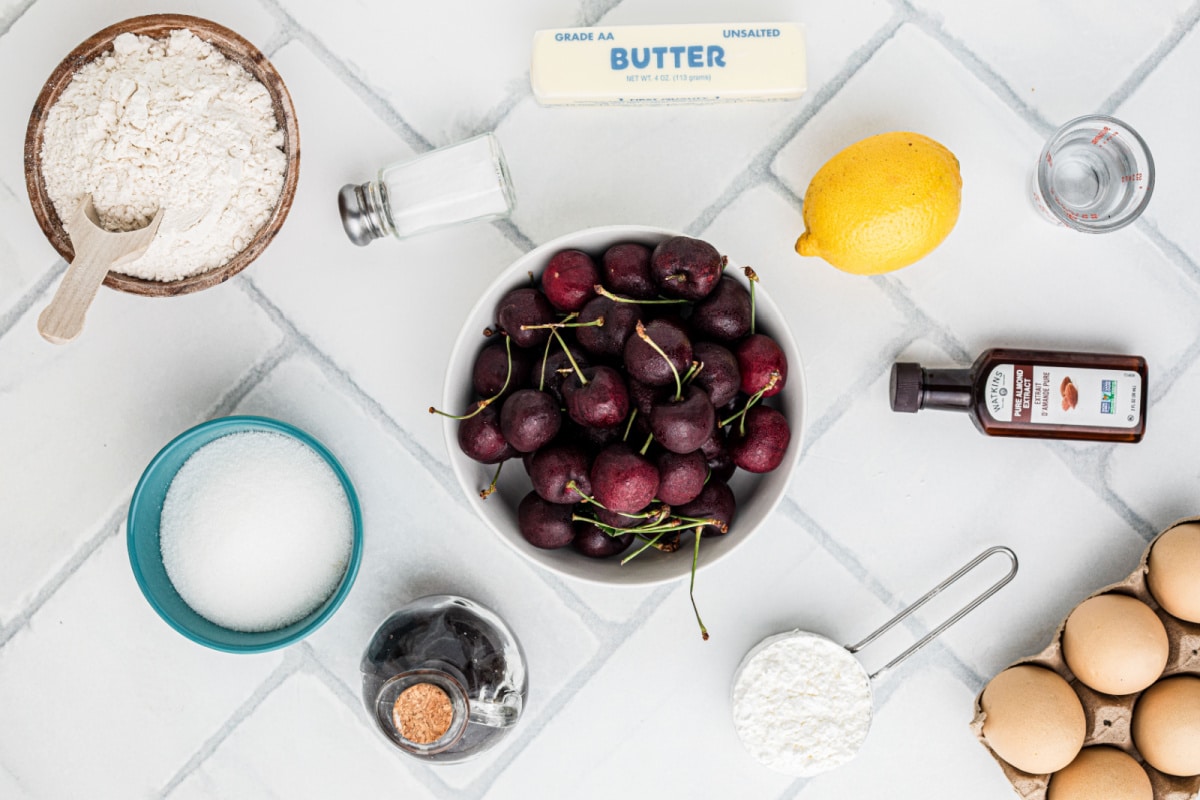 Ingredients for Fresh Cherry Pie including fresh cherries, flour, butter, sugar, lemon, cornstarch, eggs, and almond extract