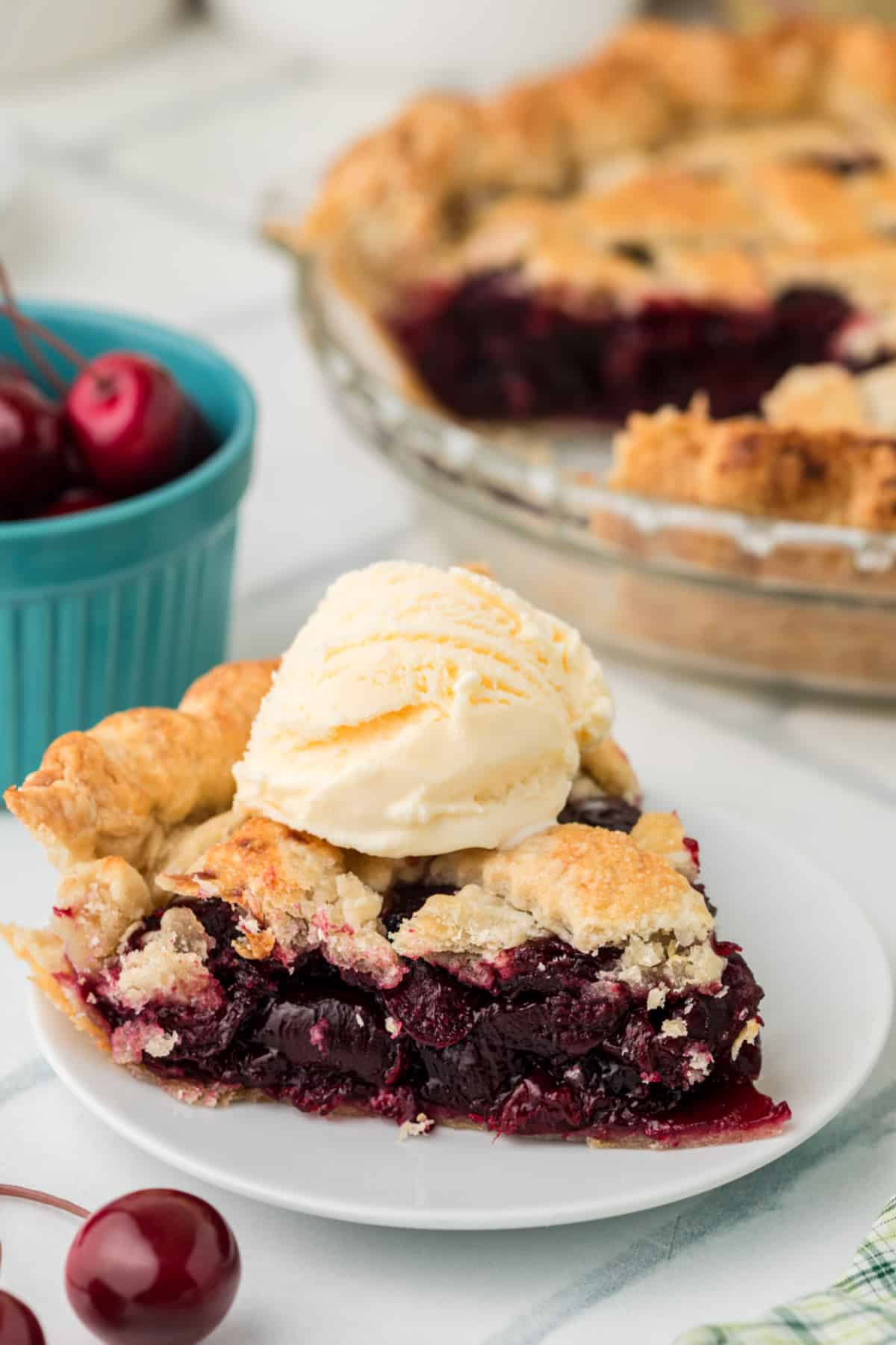 Fresh cherry pie slice topped with vanilla ice cream showing thick cherry filling and flaky homemade crust
